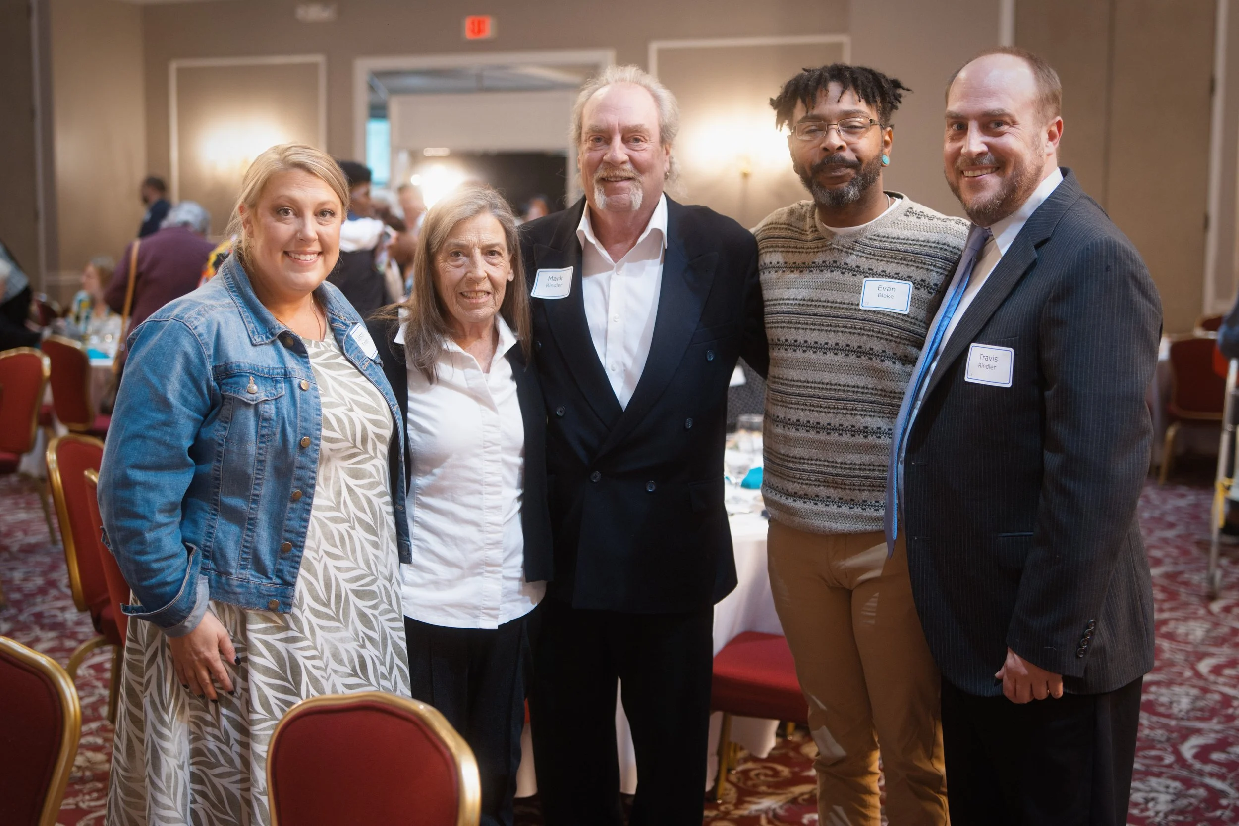 Group of attendees posing at a nonprofit fundraising event with soft lighting and a focus on guest interaction.