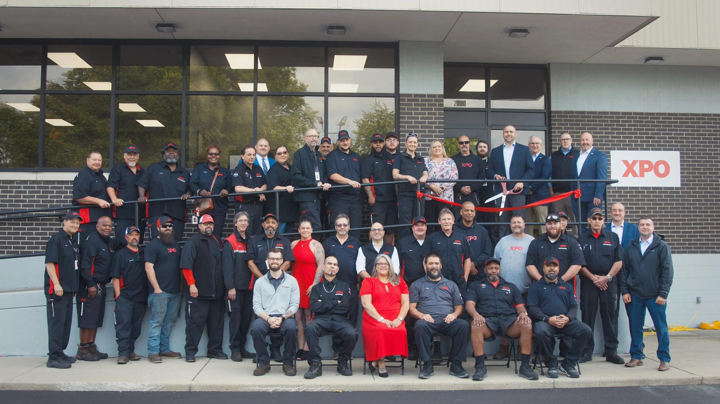 Team group photo and ribbon-cutting ceremony for a large freight company's new location, captured in natural lighting.