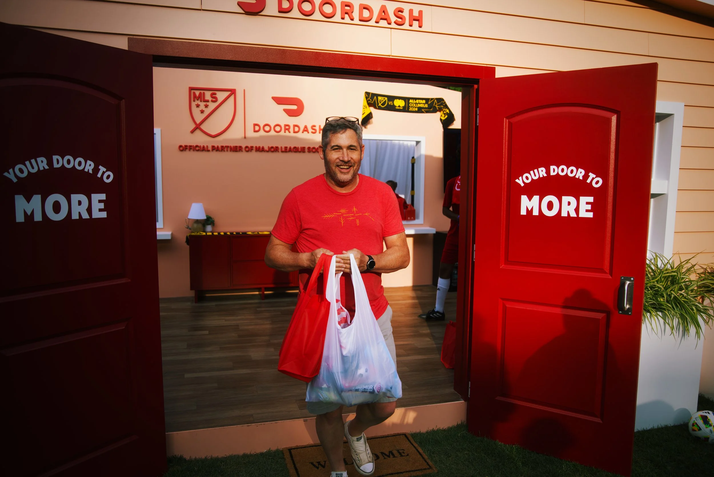 Focus on guest interactions and positive reactions, captured outside a corporate brand activation at a large Major League Soccer celebration event.