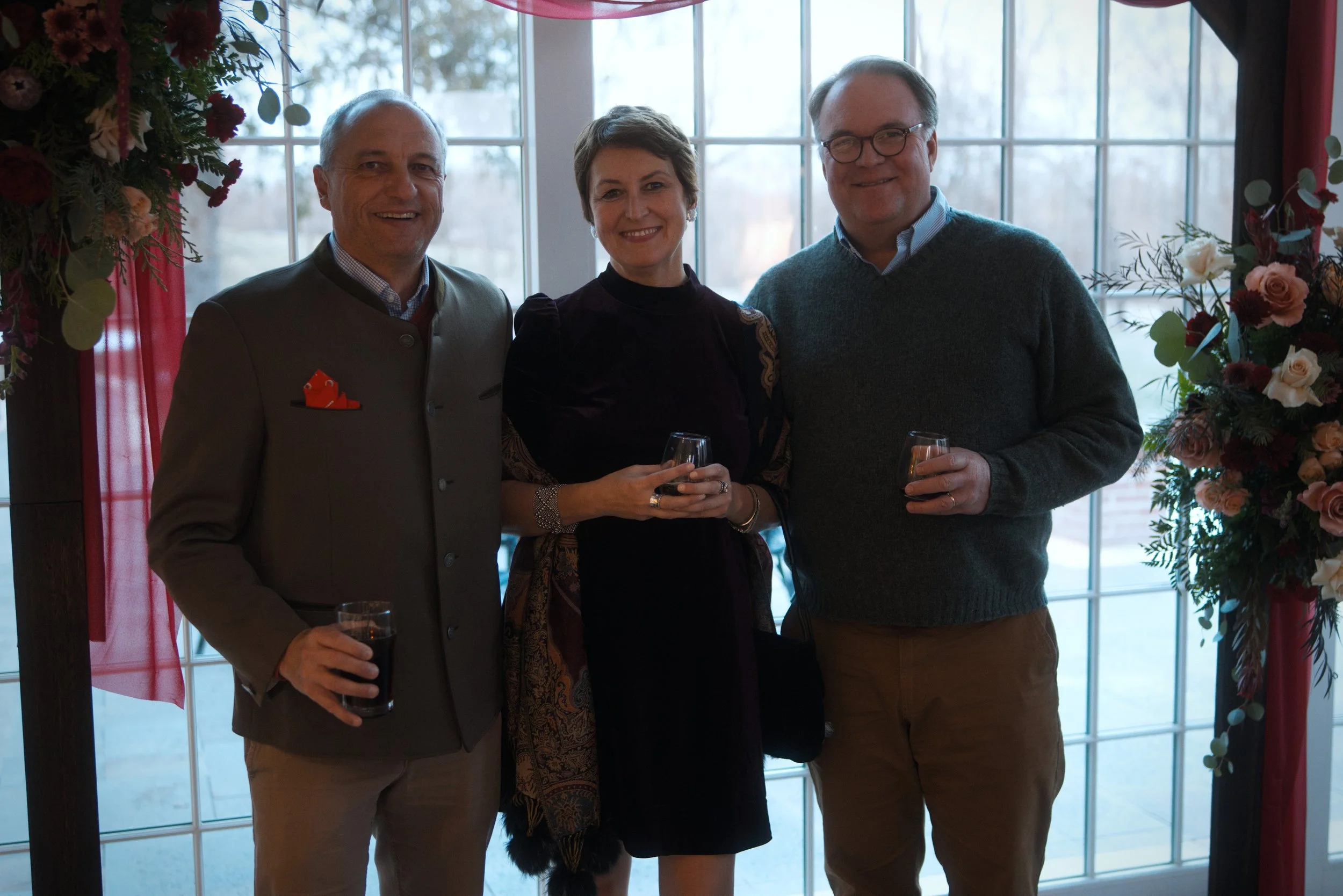 Executives pose together for a professional photographer at a corporate party event.