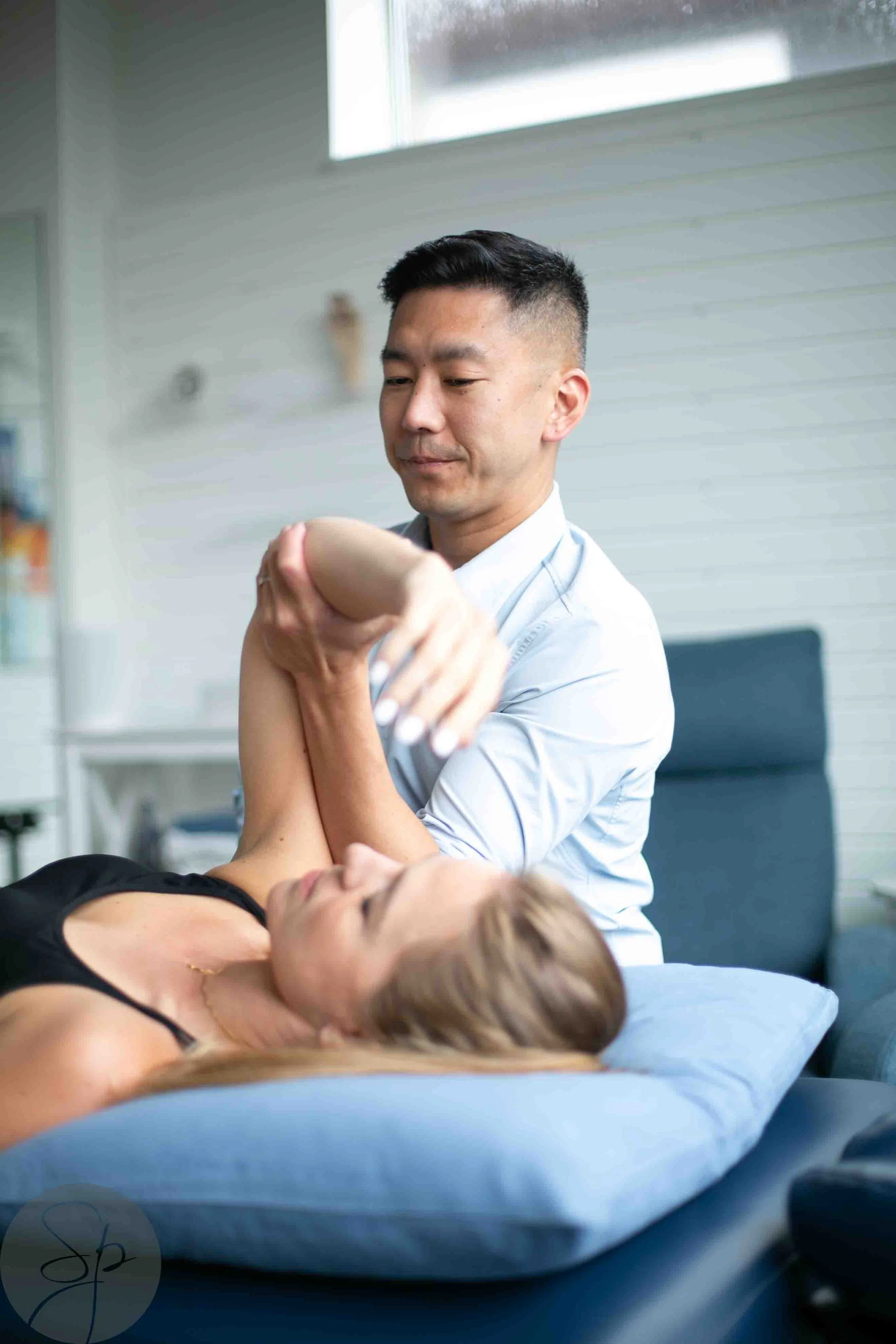 Physical therapist performing shoulder exercise on a patient lying on a table