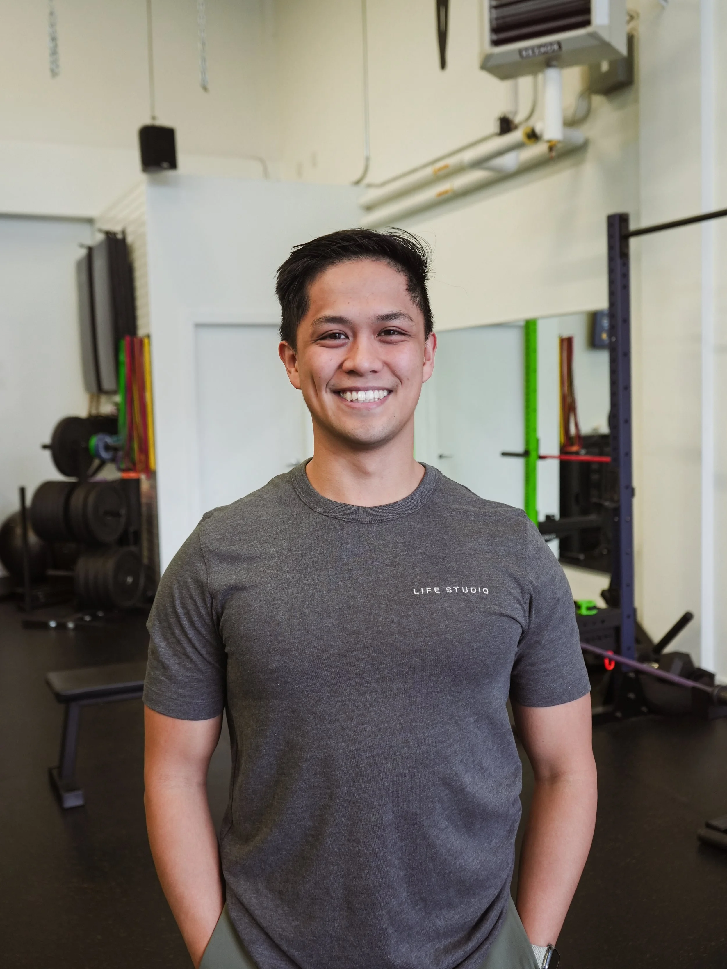 Kevin smiling, standing in a gym setting with exercise equipment in the background.