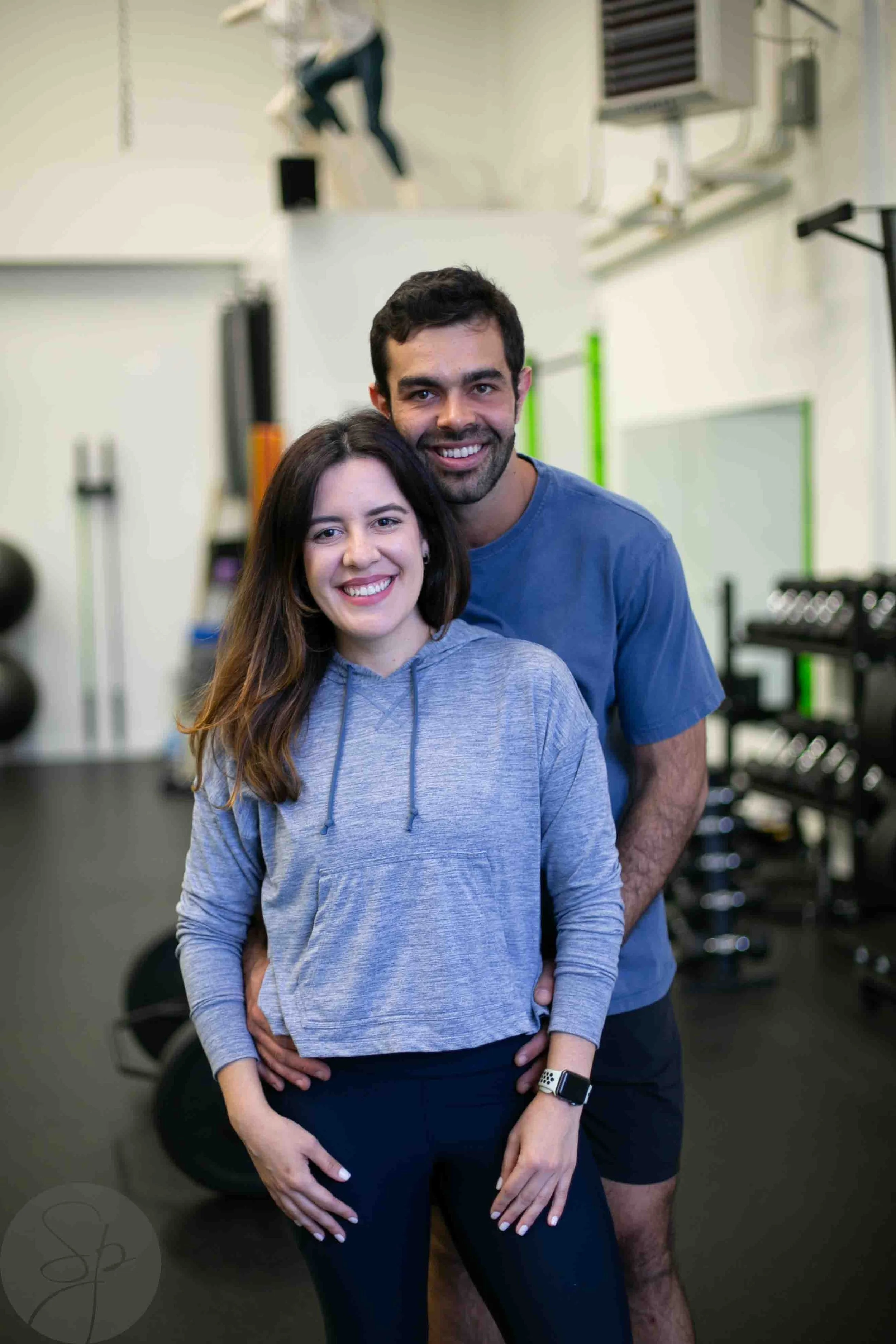 A smiling couple posing together in a gym.