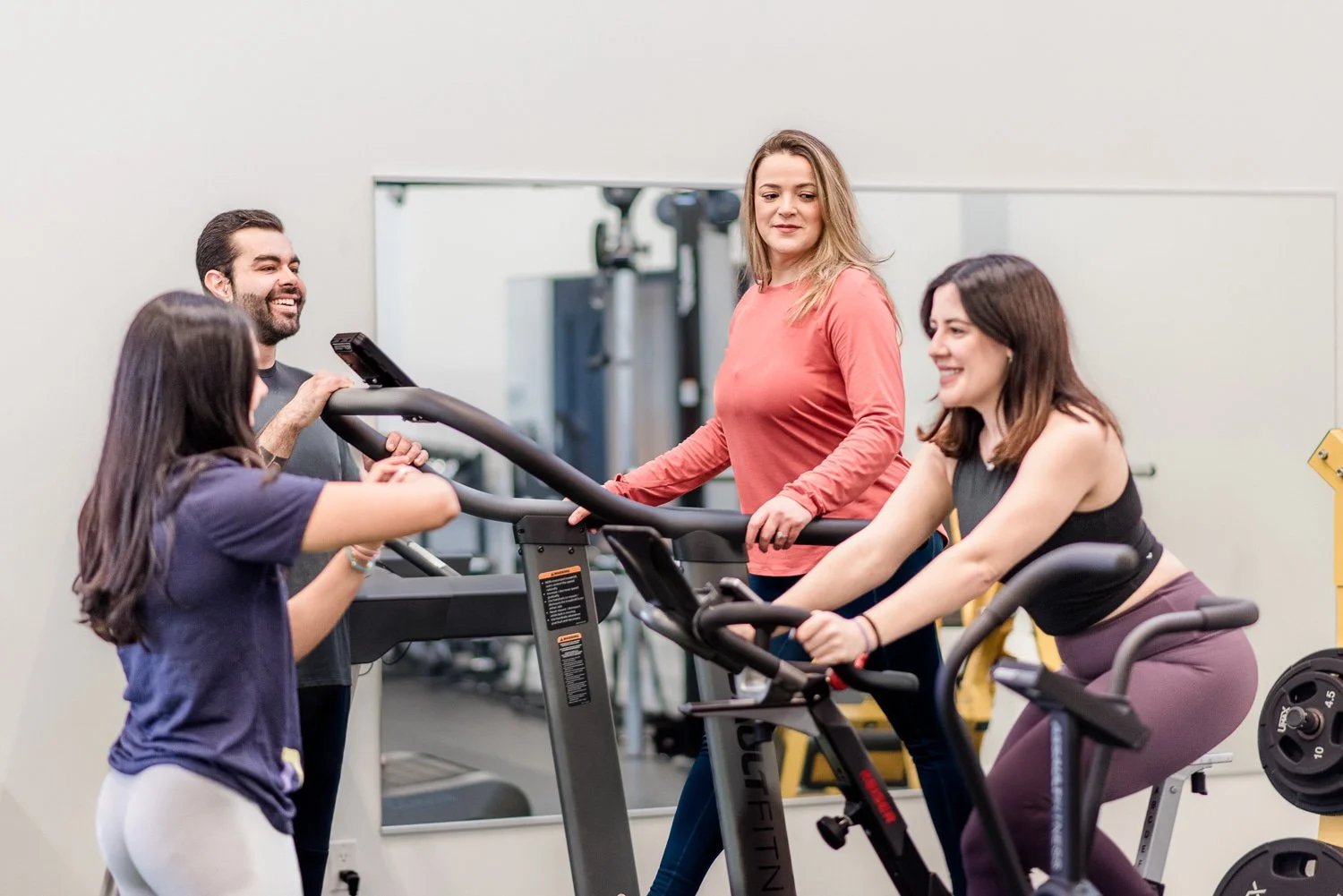 Group of people exercising on treadmills and stationary bikes in a gym.