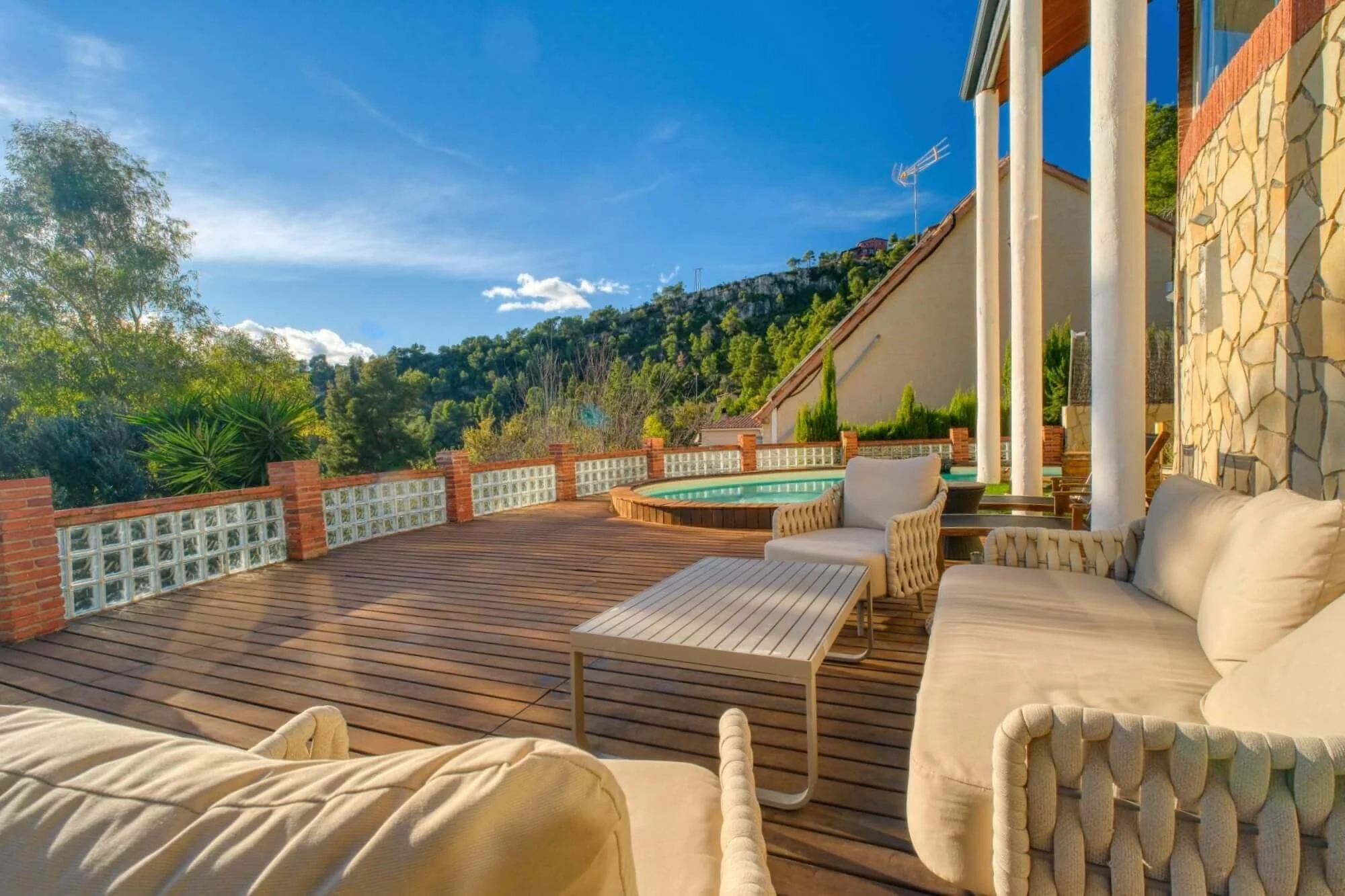 Terraza con muebles de exterior junto a piscina y vista de colinas con vegetación