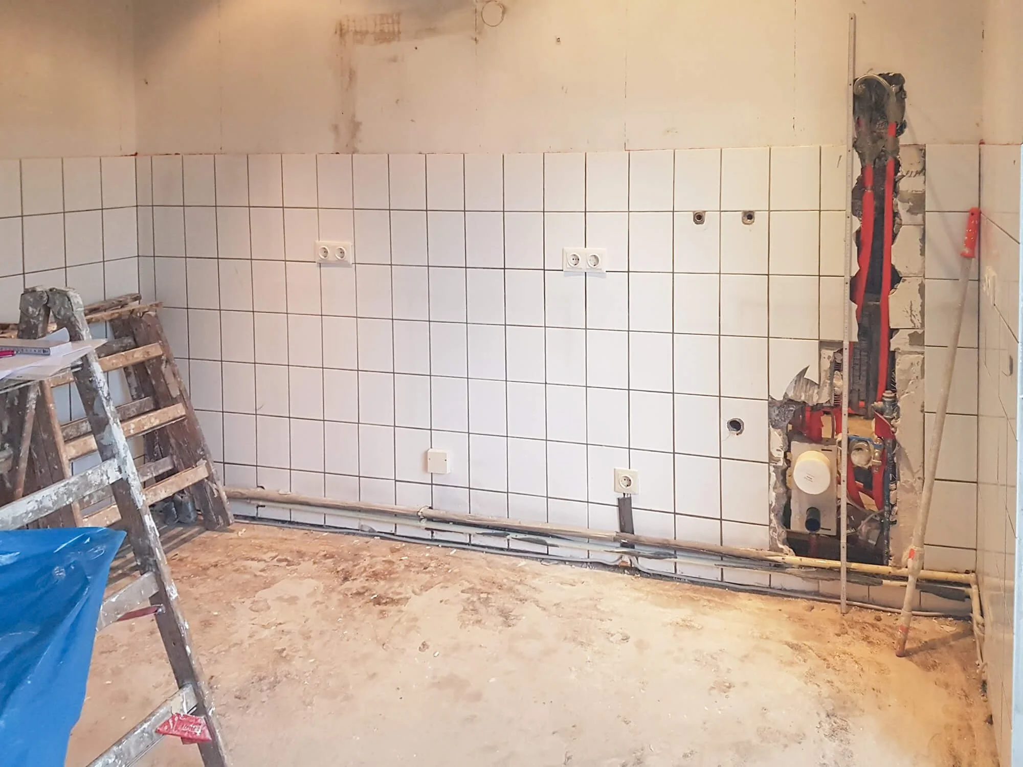 Blick auf eine Baustelle und freigelegte Installationen während einer Küchenrenovierung in Köln. Interior Designerin Berthe Dong übernimmt die Projektbegleitung.