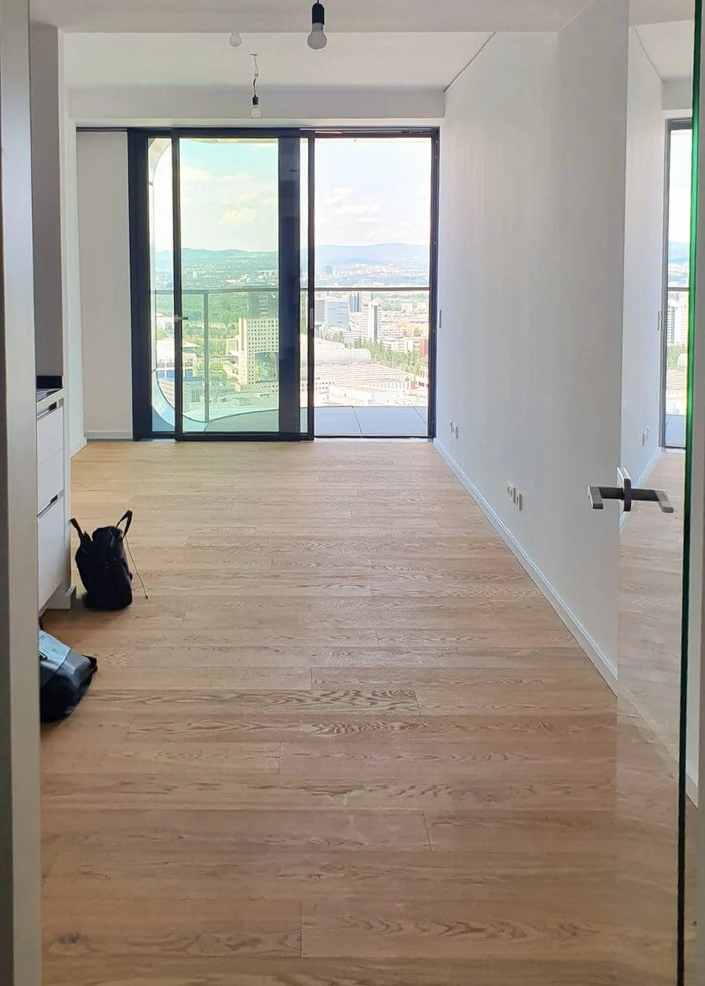 Leerer Wohnraum einer Neubauwohnung vor der Einrichtung mit bodentiefen Fenstern und Skylineblick im Grand Tower Frankfurt.