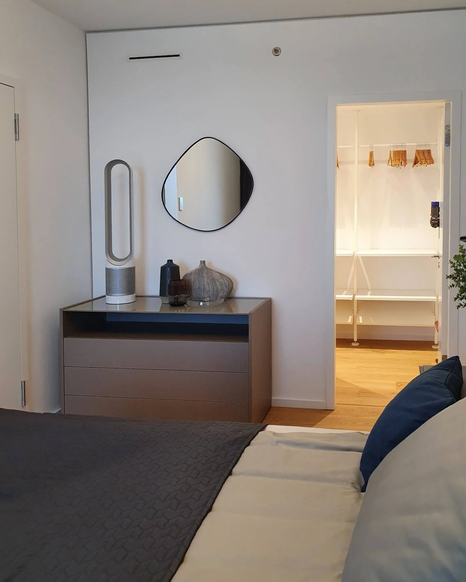 Schlafzimmer mit Kommode, Spiegel und Zugang zur offenen Ankleide in einer Neubauwohnung im Grand Tower Frankfurt, Interior Design von Berthe Dong.