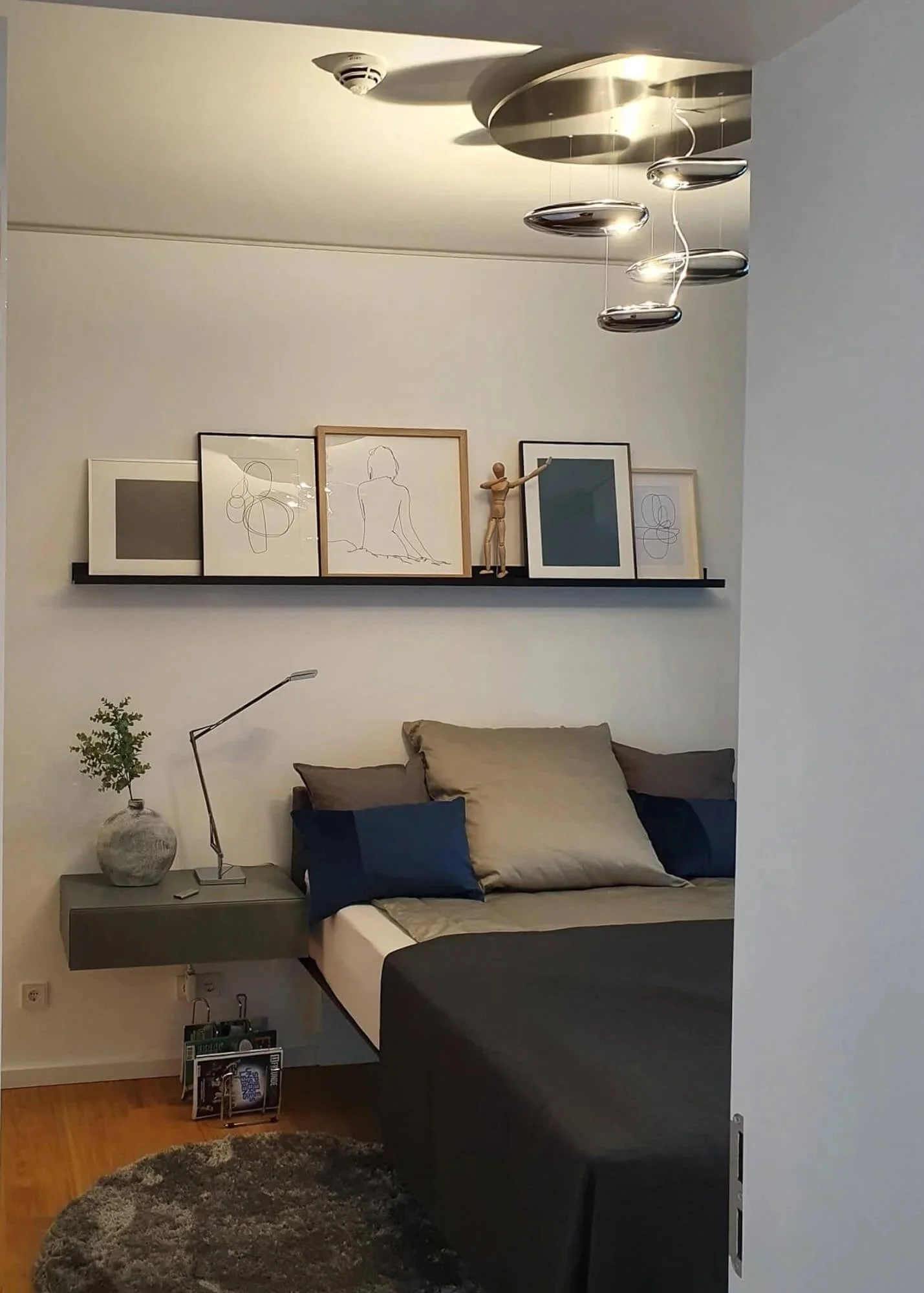 Minimalistisches Schlafzimmer mit schwebendem Bett, Bilderleiste und warmem Holzparkett in einer Neubauwohnung im Grand Tower Frankfurt von Berthe Dong.
