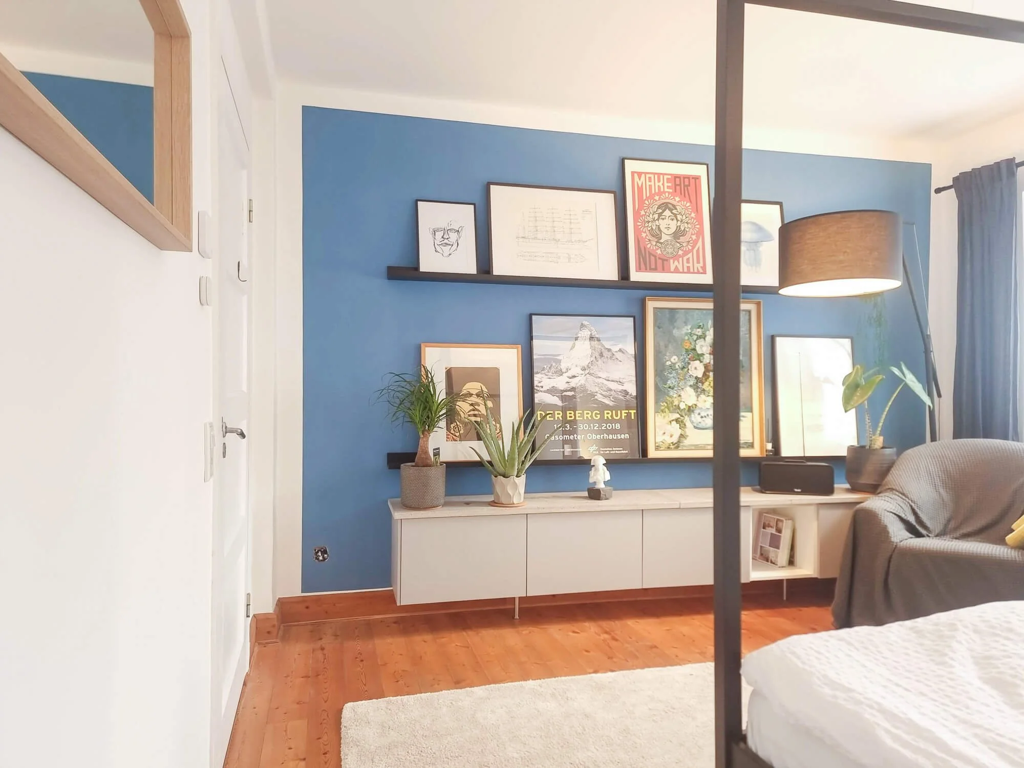 Detailansicht der Wandgestaltung mit blauer Wandfarbe, Galerie-Wand und modernem Sideboard im Aachener Schlafzimmer-Projekt .