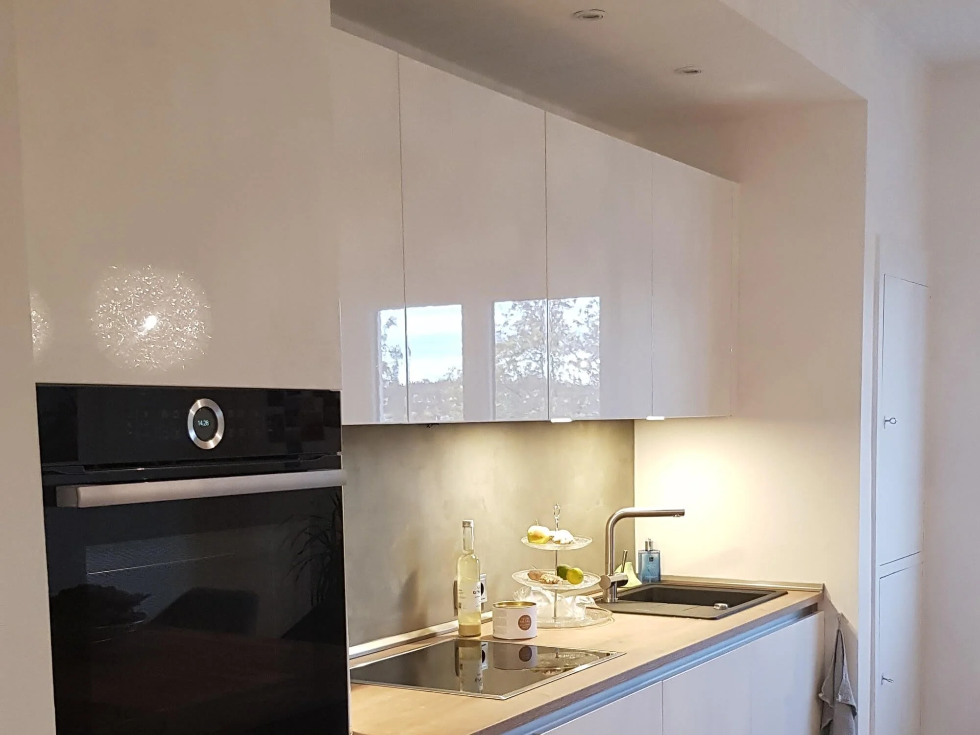 Moderne weiße Einbauküche mit klaren Fronten und integrierten Geräten in einer renovierten Kölner Eigentumswohnung.