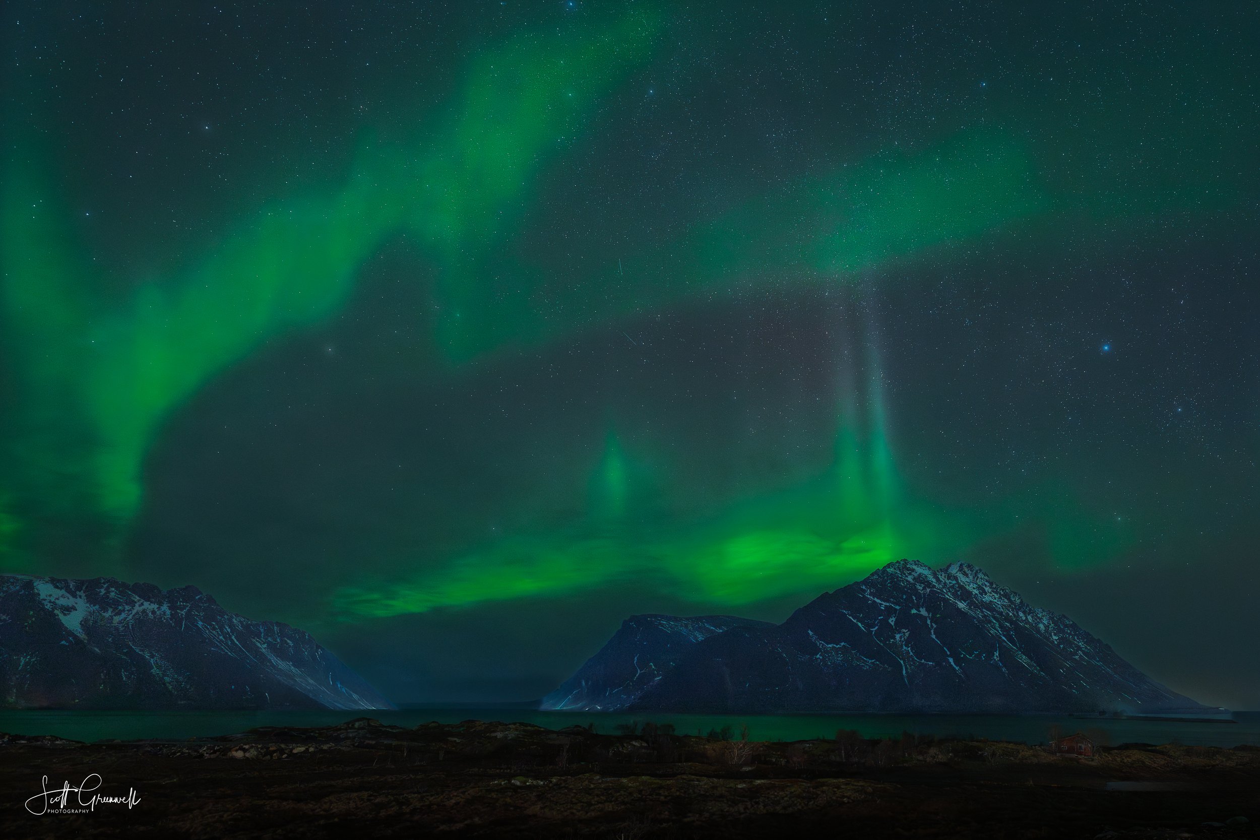 Crownfire - Bands of light stretch across the sky in layered formations, hovering above darkened ridgelines. The intensity of the aurora transforms the landscape into something otherworldly yet grounded in silence.
