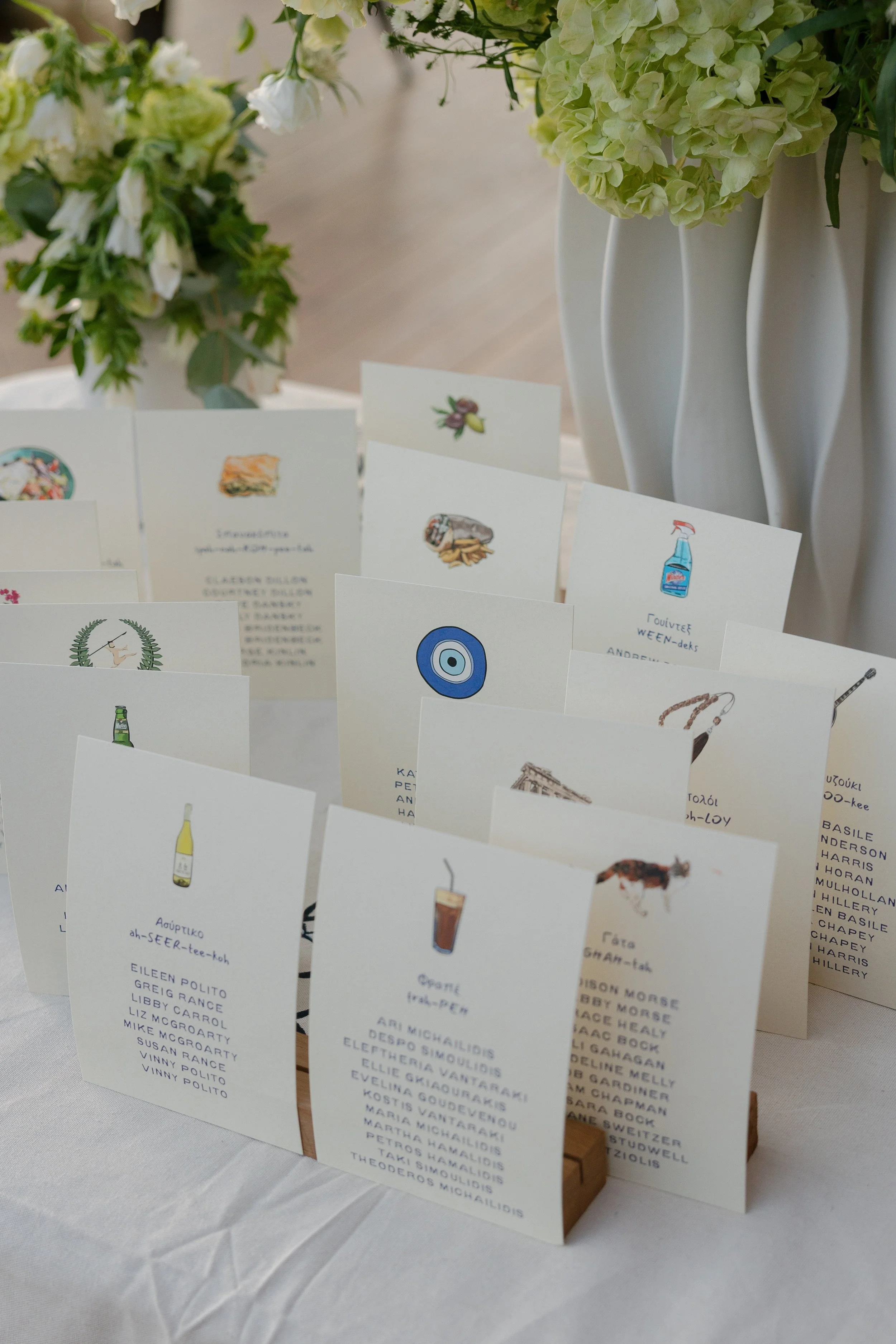 Close-up of a wedding display with Greek-themed place cards featuring hand-drawn illustrations