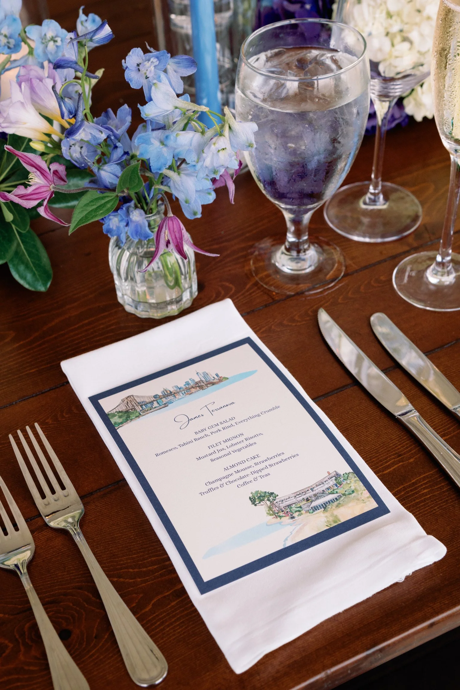A table setting with a bespoke wedding menu showing both NYC skyline and Chatham Bars in Cape Cod