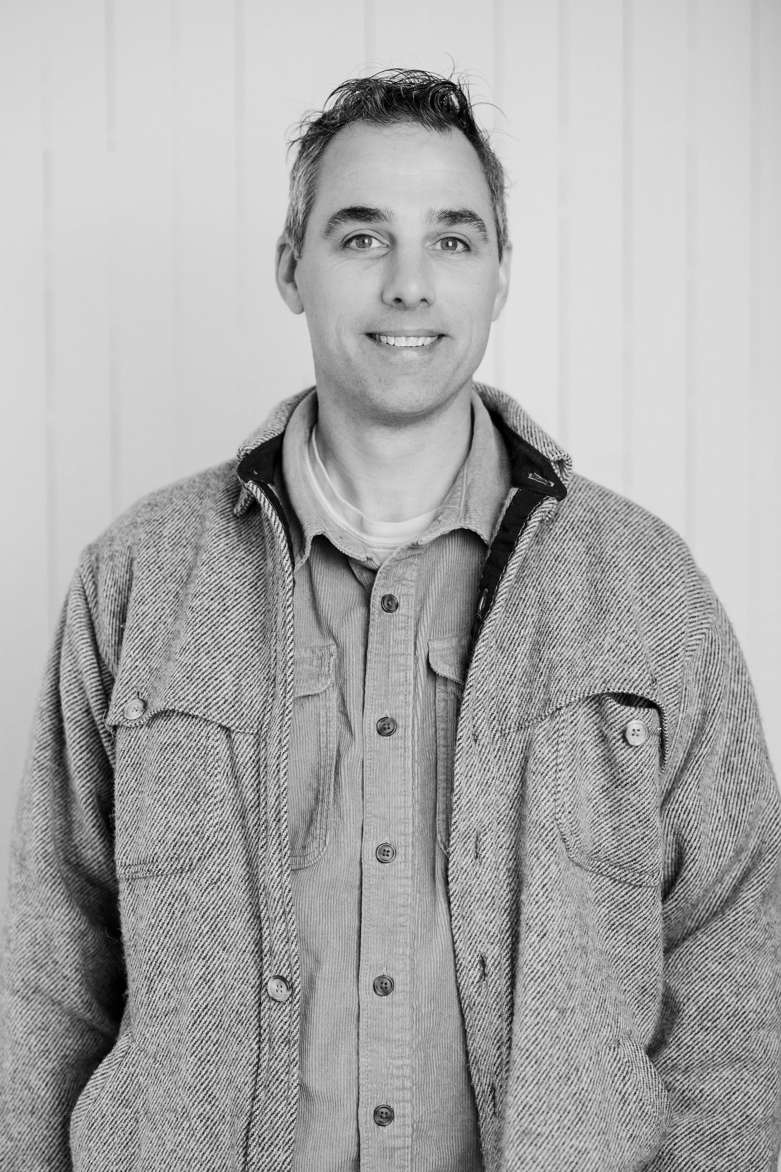 Man in a Patagonia jacket standing against a weathered wooden wall.