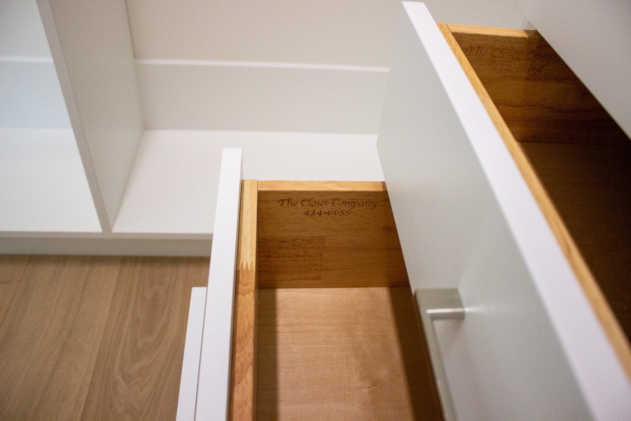 beach side home with new closet featuring white slab dressers, shaker fronts and warm coastal wood grain closets.  