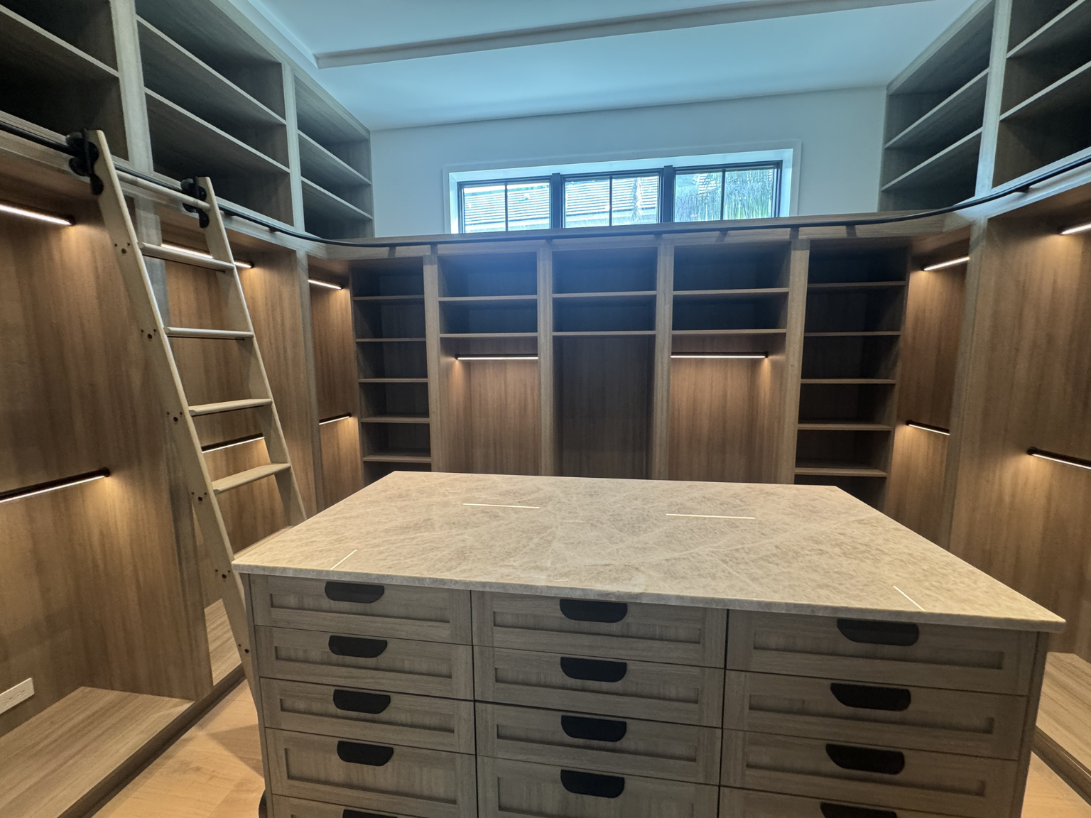 custom closet with large island and lighting 