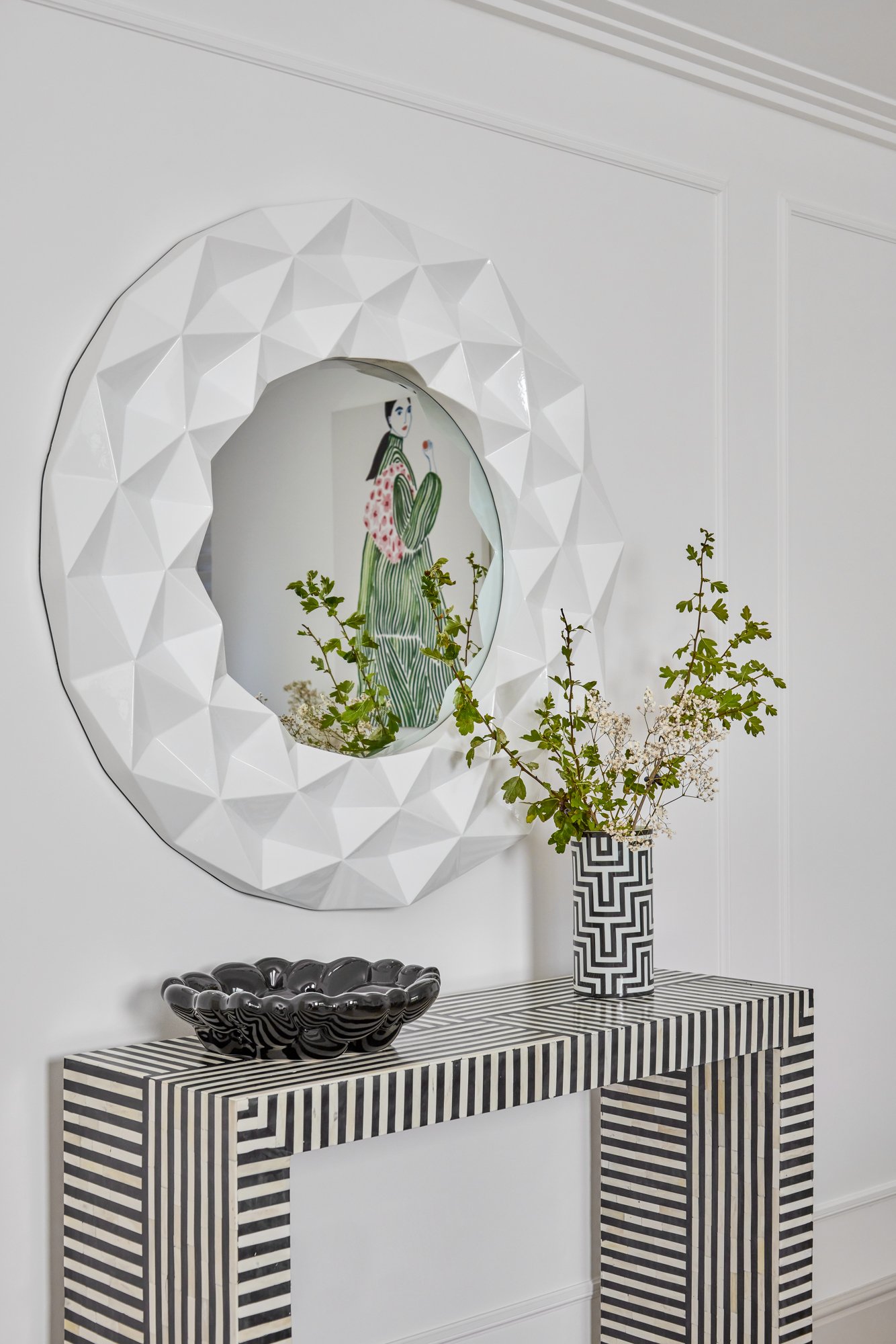 Wimbledon living room with geometric mirror above striped console table and decorative accents.