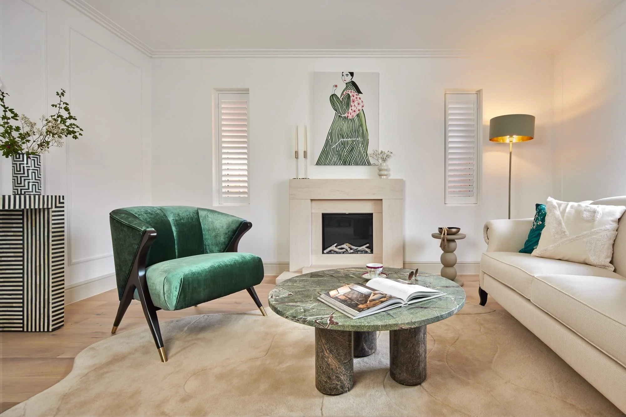 Wimbledon living room with vintage-style green velvet armchair as the statement piece against a contemporary marble coffee table and neutral sofa.