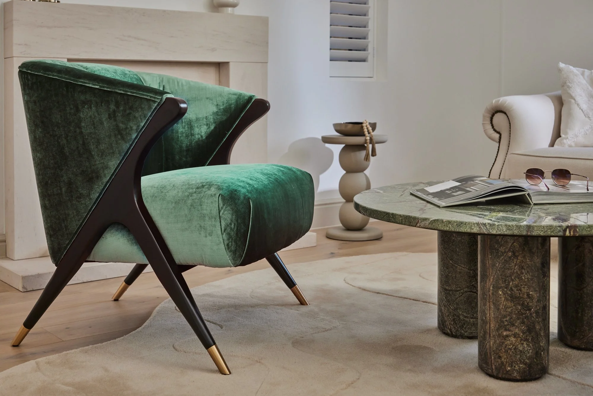 Living room with green velvet armchair, white sofa with pillow, marble-top round coffee table, small side table from our Wimbledon project 
