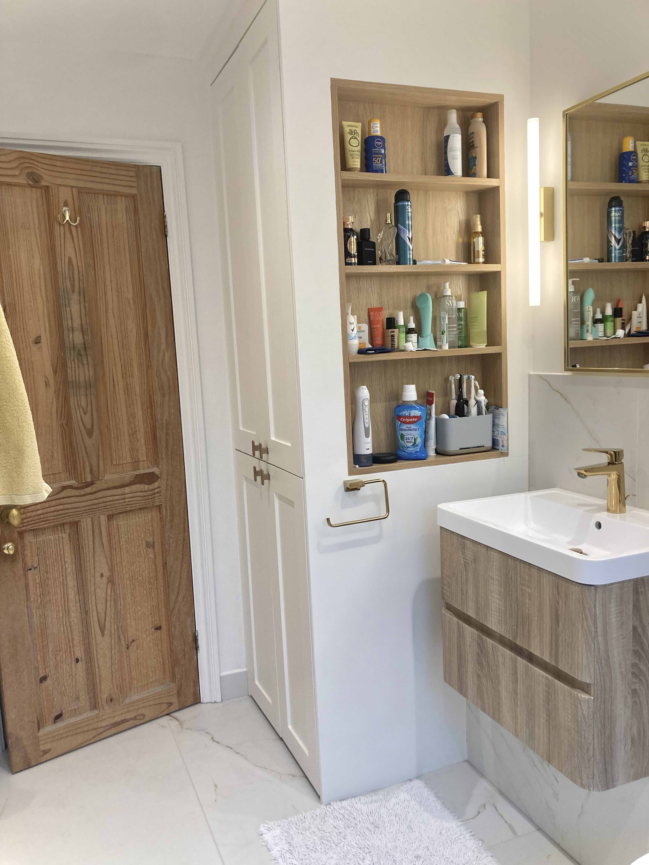 Bespoke bathroom vanity with oak-effect cabinetry, illuminated mirror cabinet and brass fittings in our Kingston project