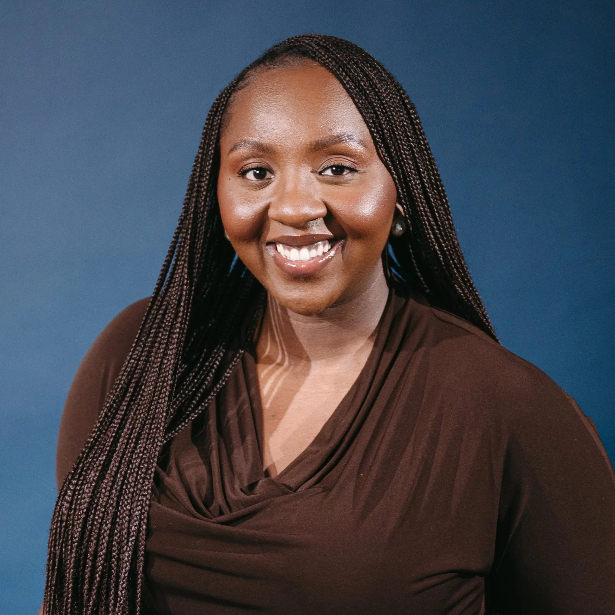 Behavioural consultant in Edmonton Alberta wearing a brown shirt standing against a blue backdrop