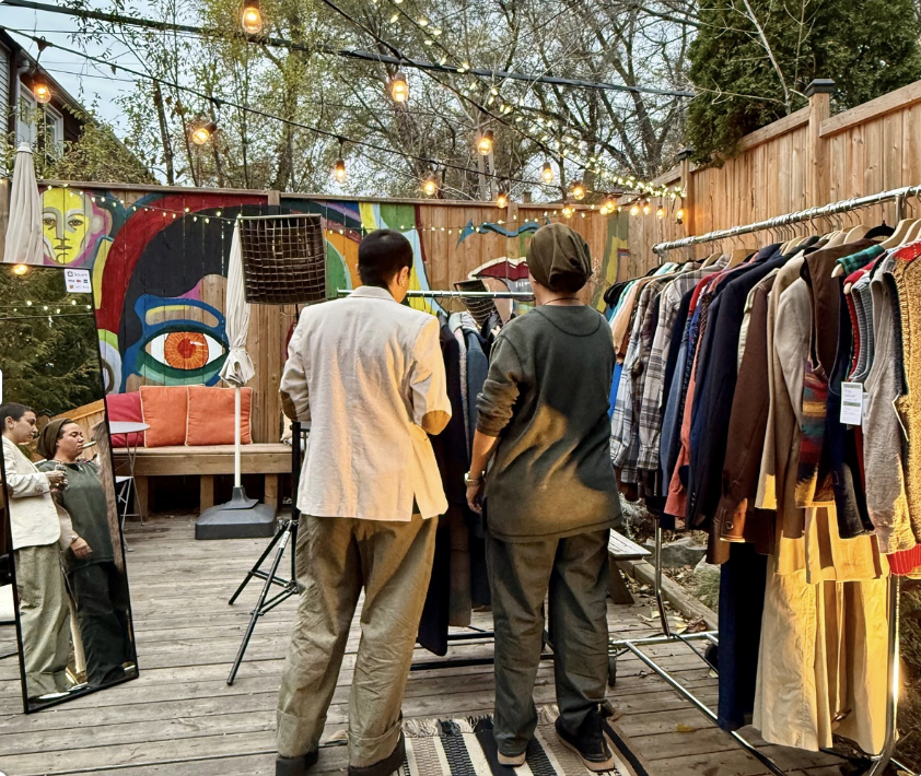 Two people on the outside patio space looking at clothing from a clothes swap hosted at Morning Parade's Upper Beaches cafe.