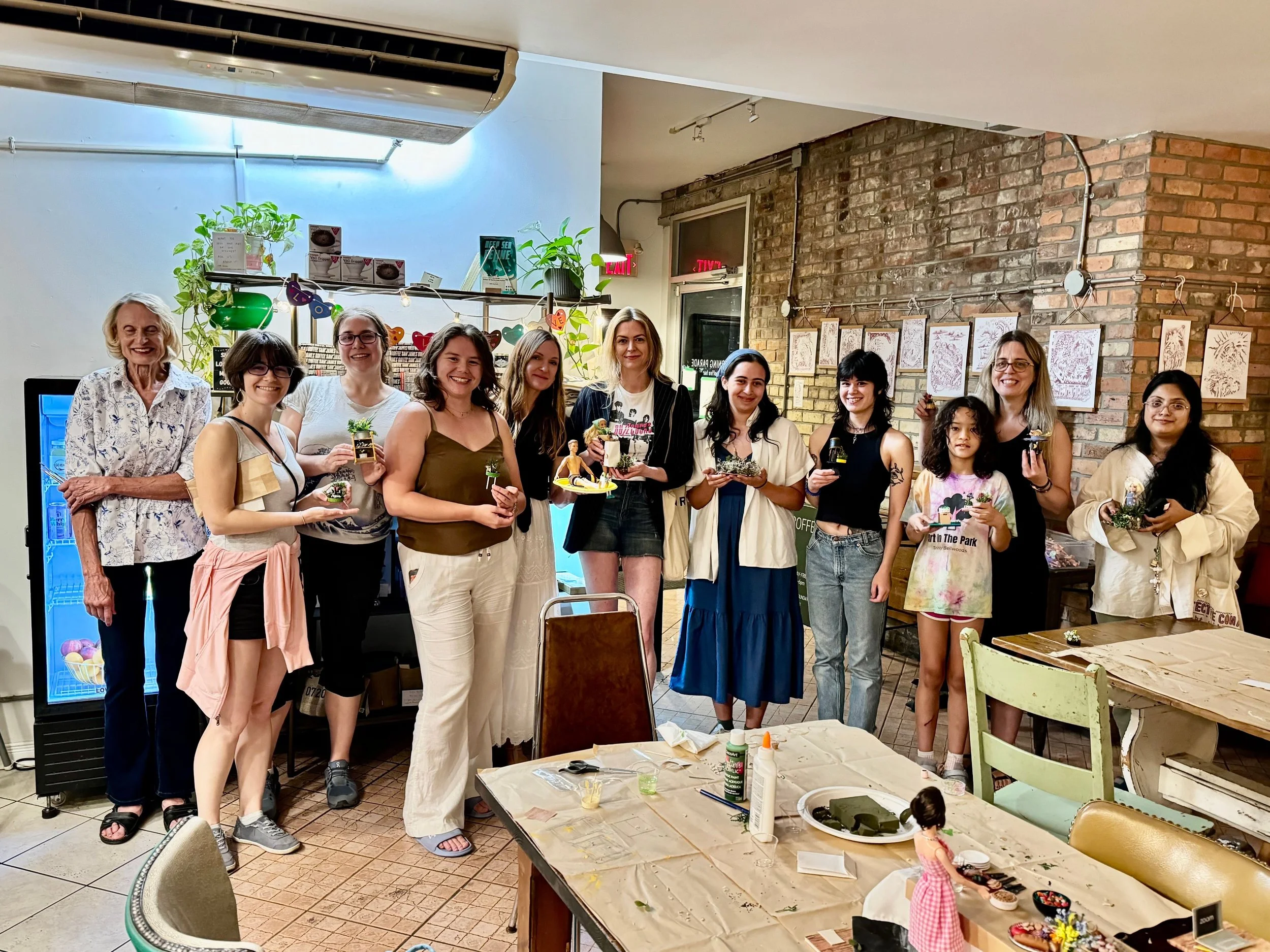 A group photo of people holding their finished miniatures, taken from an event in Morning Parade's Trinity Bellwoods cafe location.