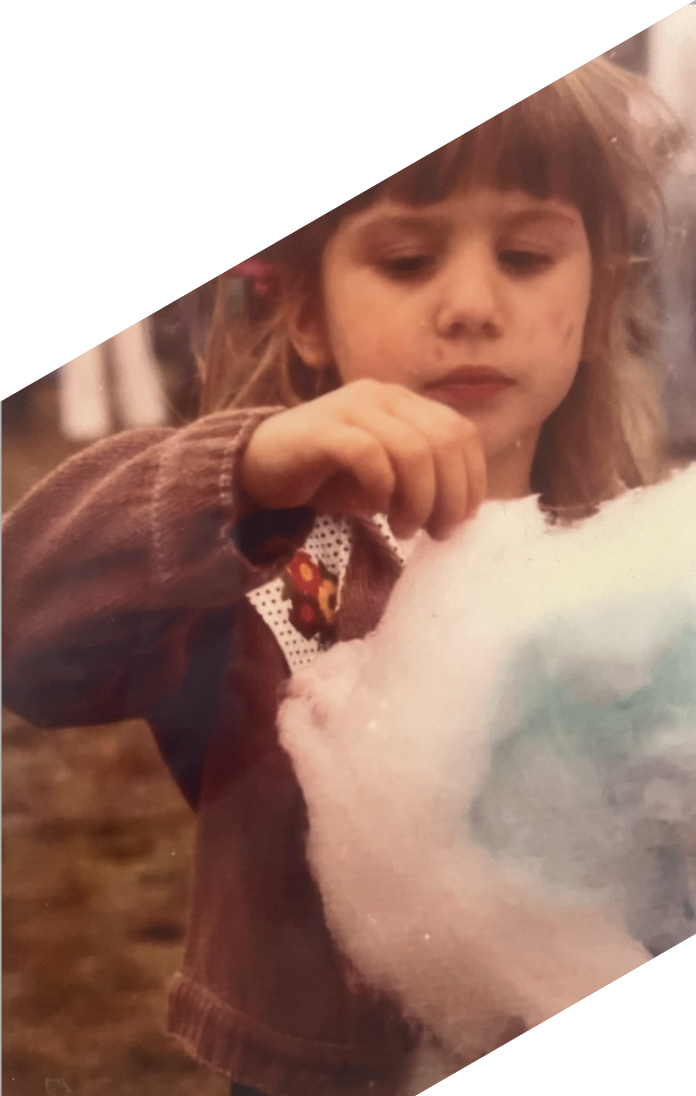 Young girl holding cotton candy outdoors.