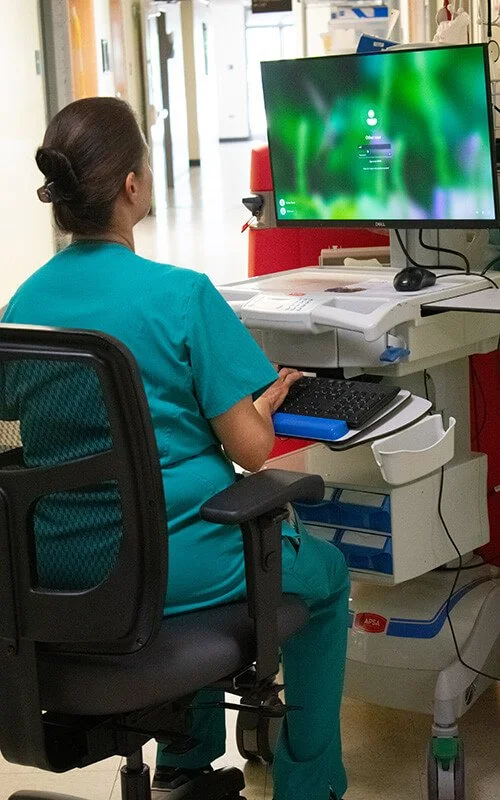 North Runnels Hospital nurse working at a clinical computer station while supporting patient care in Winters, Texas.