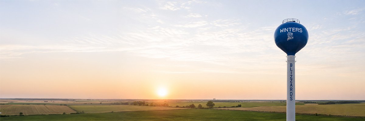 Sunset over Winters, Texas farmland with the Winters Blizzards water tower, representing the community served by North Runnels Hospital District.