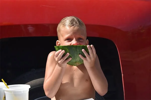 Child enjoying watermelon at a community event in the North Runnels area, highlighting family-focused community involvement.