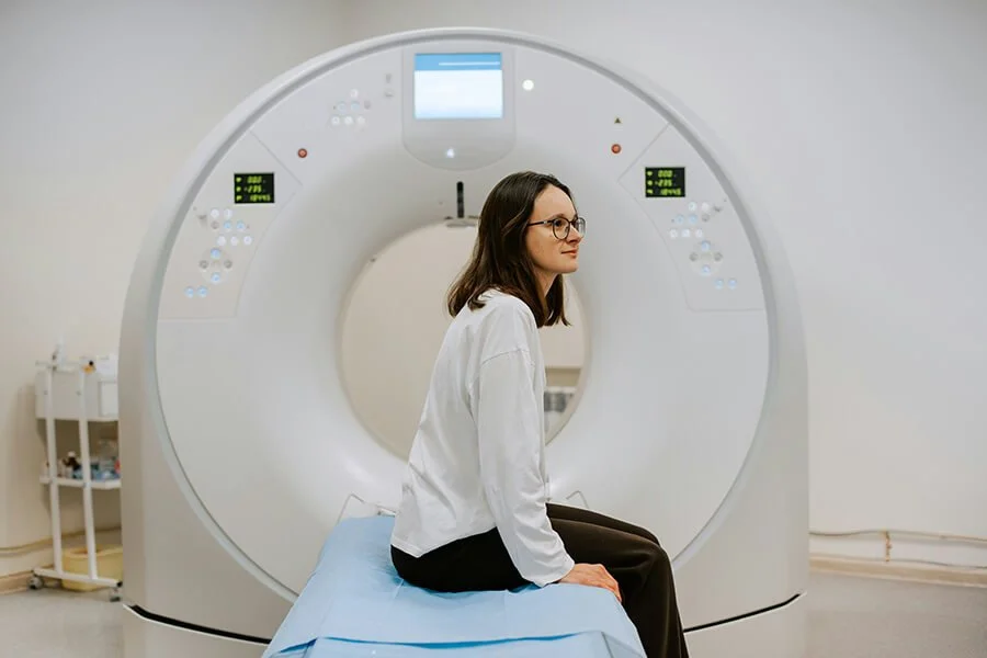 Patient waiting to get CT scan, sitting on bed