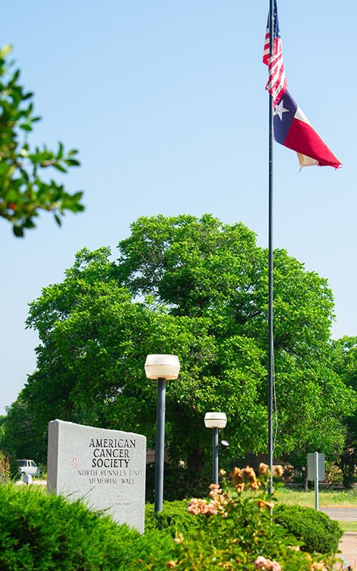 American and Texas flags near the North Runnels Unit American Cancer Society Memorial Wall in Winters, Texas.