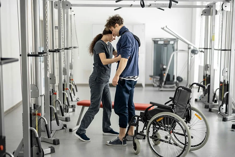 Woman helping man stand up from wheel chair, rehabilitation at North Runnels Hospital District