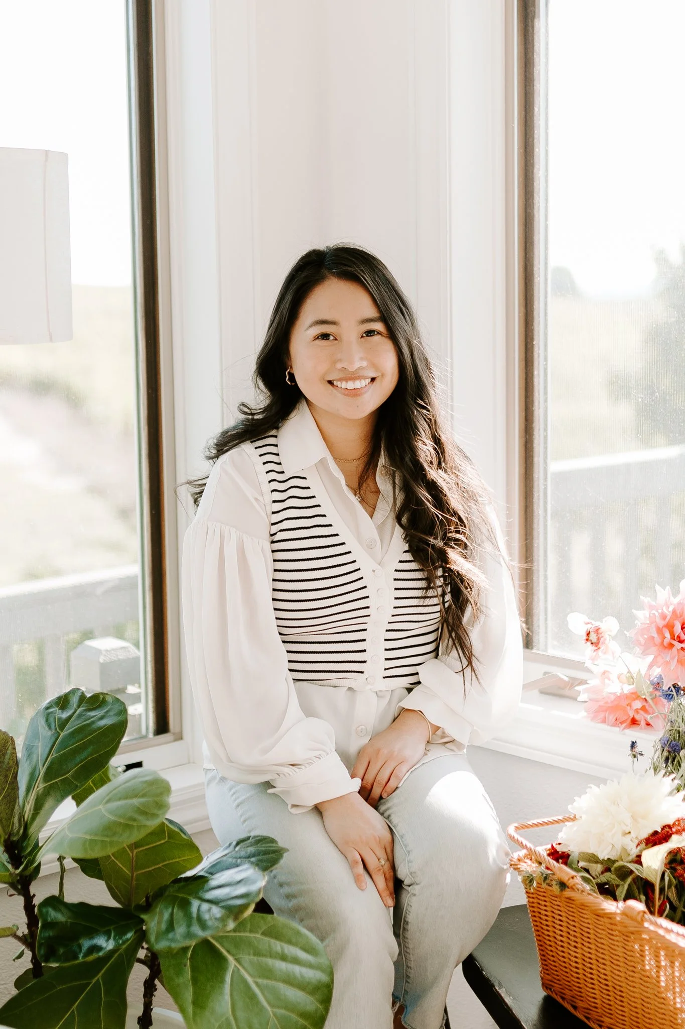 Woman sitting by window with plant and flowers in basket