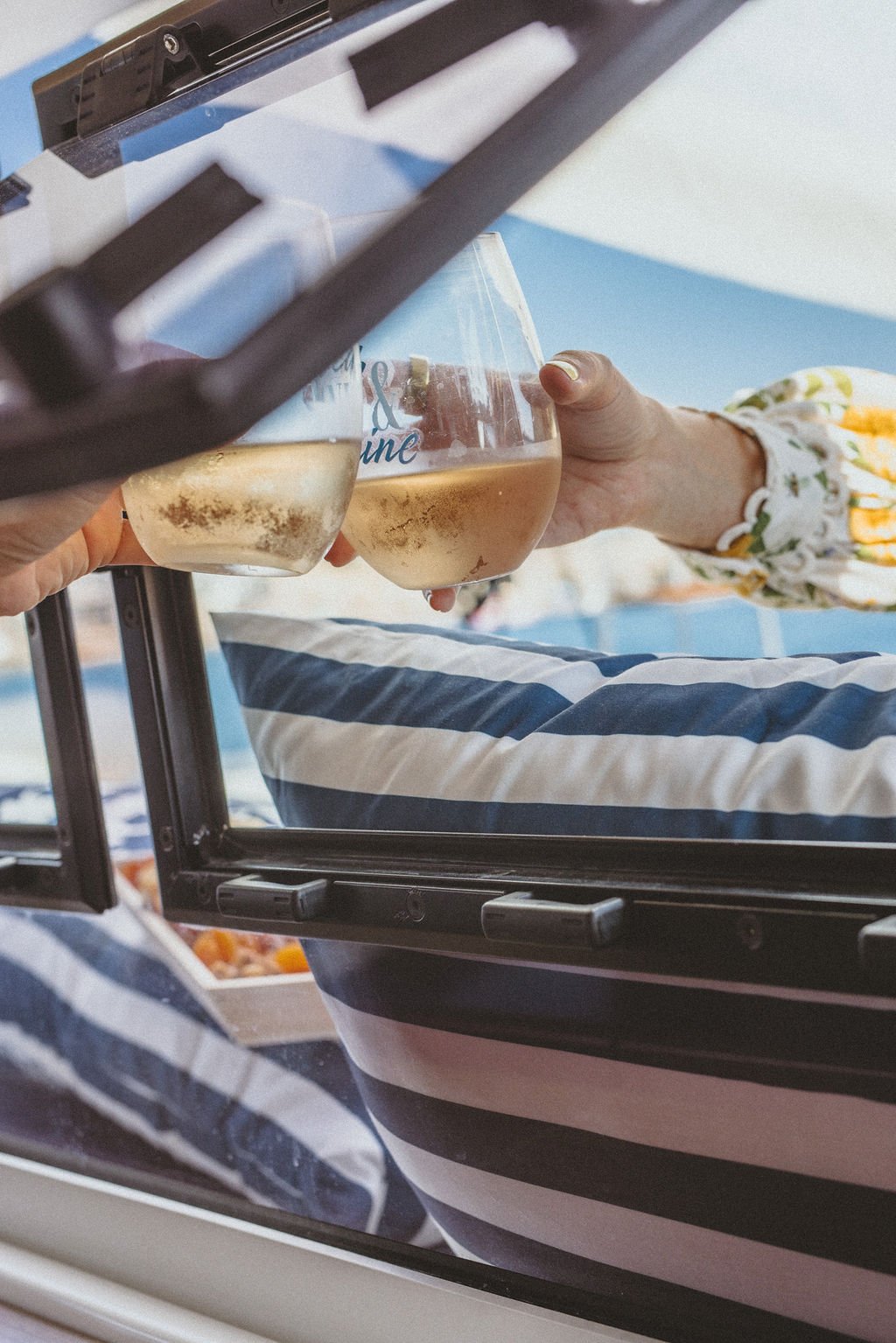A woman on a tennis court holding a tennis racket and a tennis ball, wearing a white outfit, cap, and sneakers.