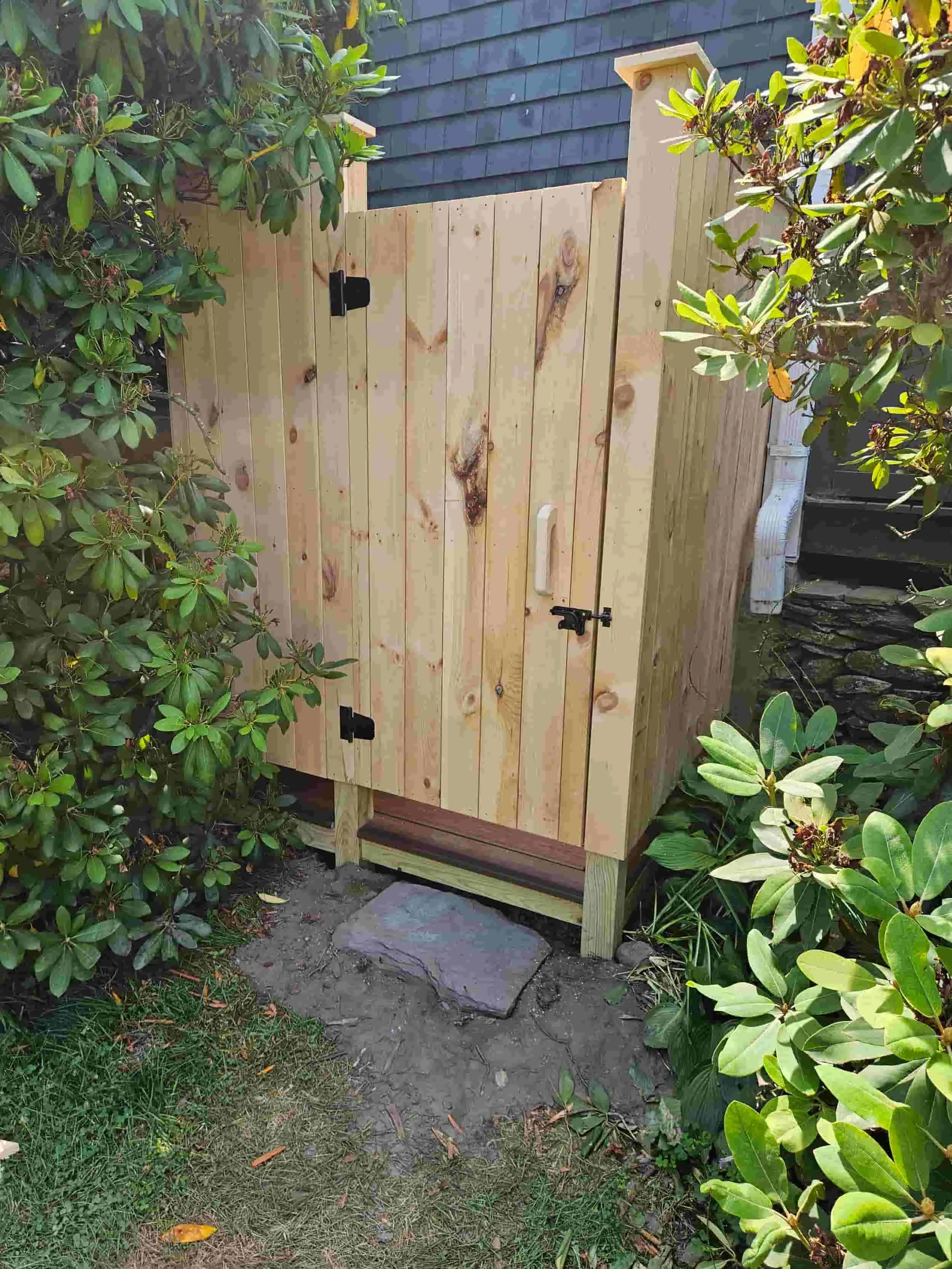 Pressure treated wood outdoor shower enclosure in Portsmouth Rhode Island, featuring clean vertical boards, a privacy door, and durable construction for coastal living. People love the outdoor showers toensing construction builds.