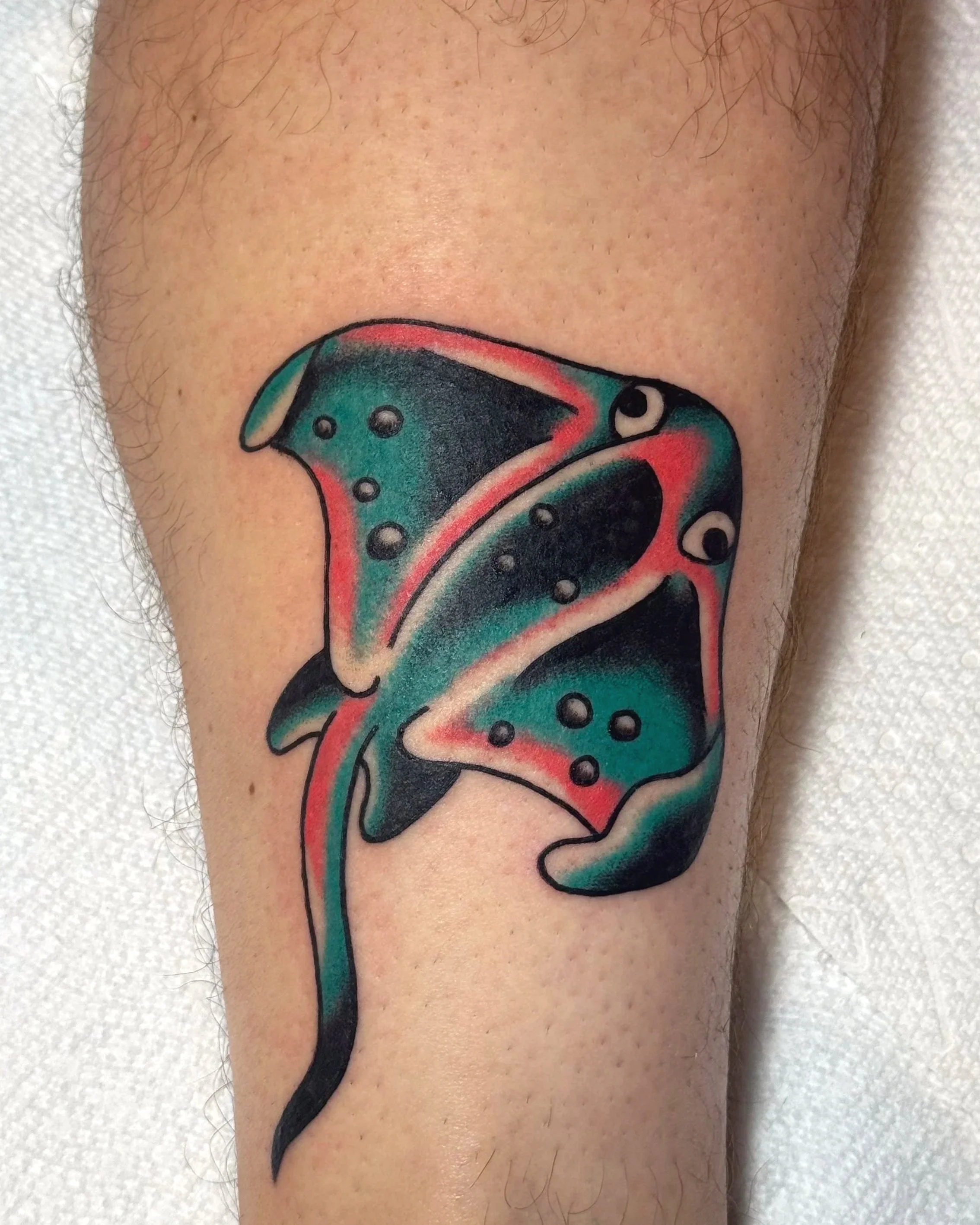Colorful tattoo of a cartoonish-looking stingray on a person's arm with a vibrant design and shading.
