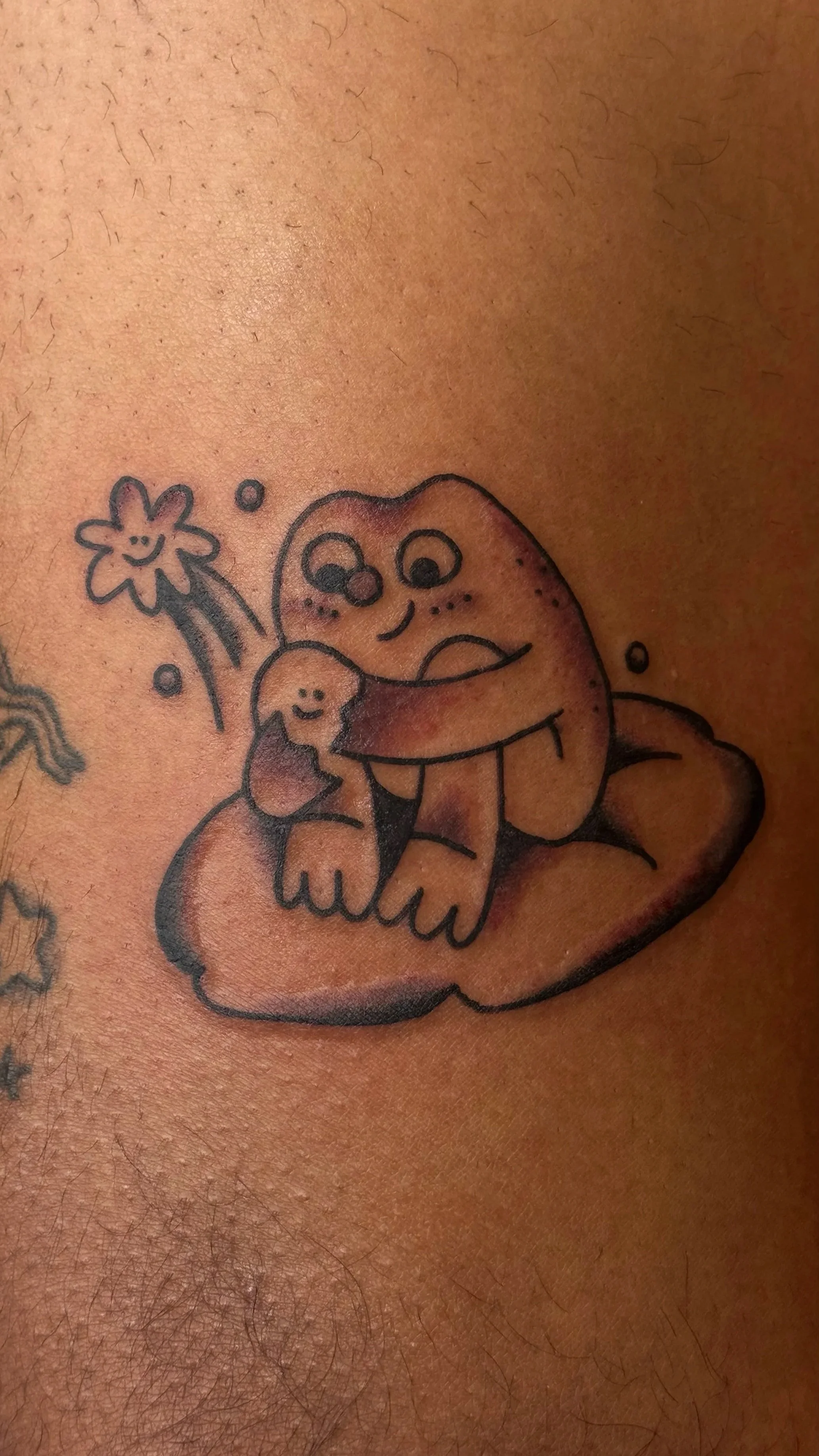 A colorful cartoon-style tattoo of a happy, smiling, gray cat with big eyes, sitting on a cloud, with a small happy star nearby.