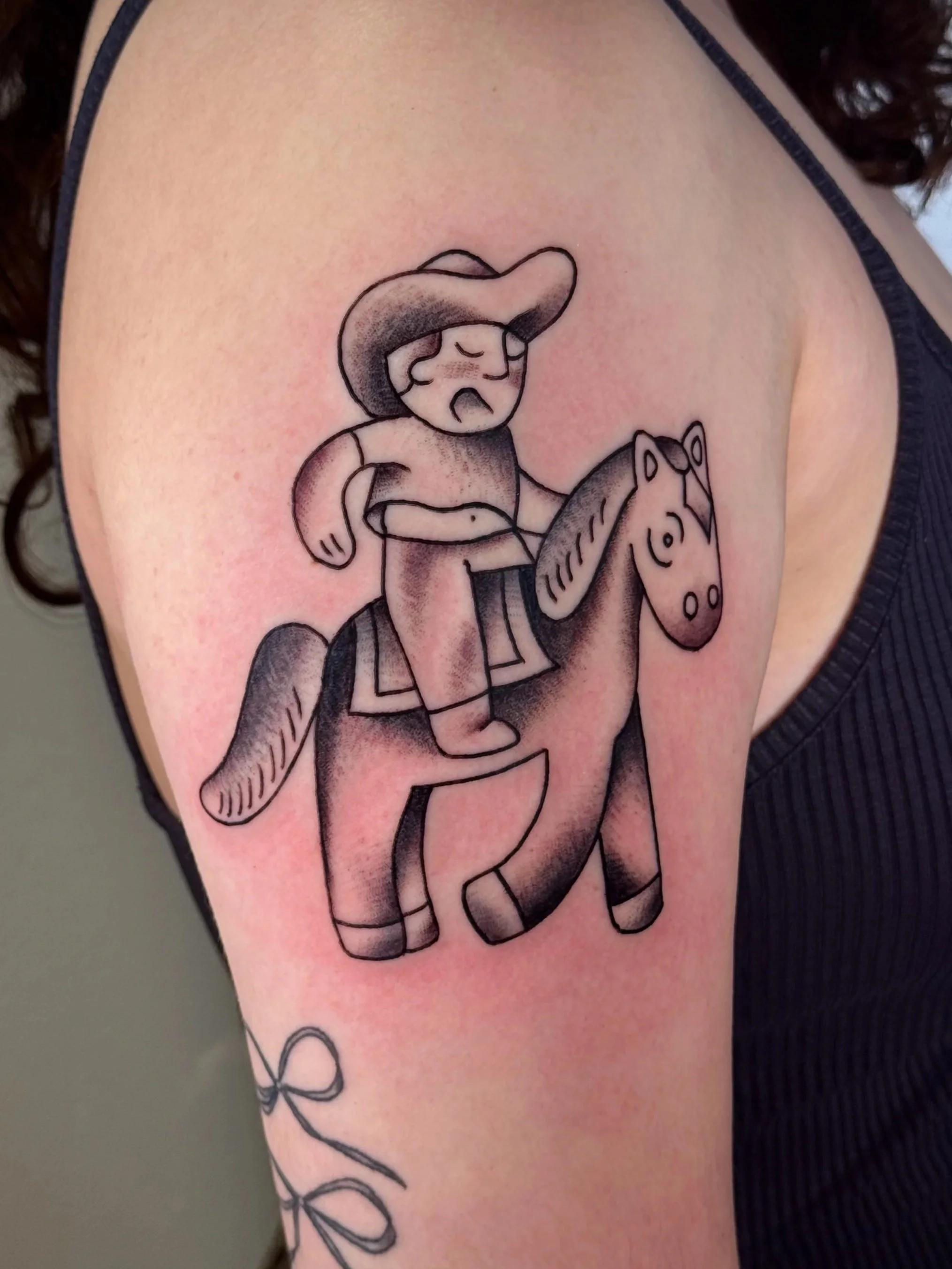 Tattoo of a cartoon person riding a horse on a shoulder.