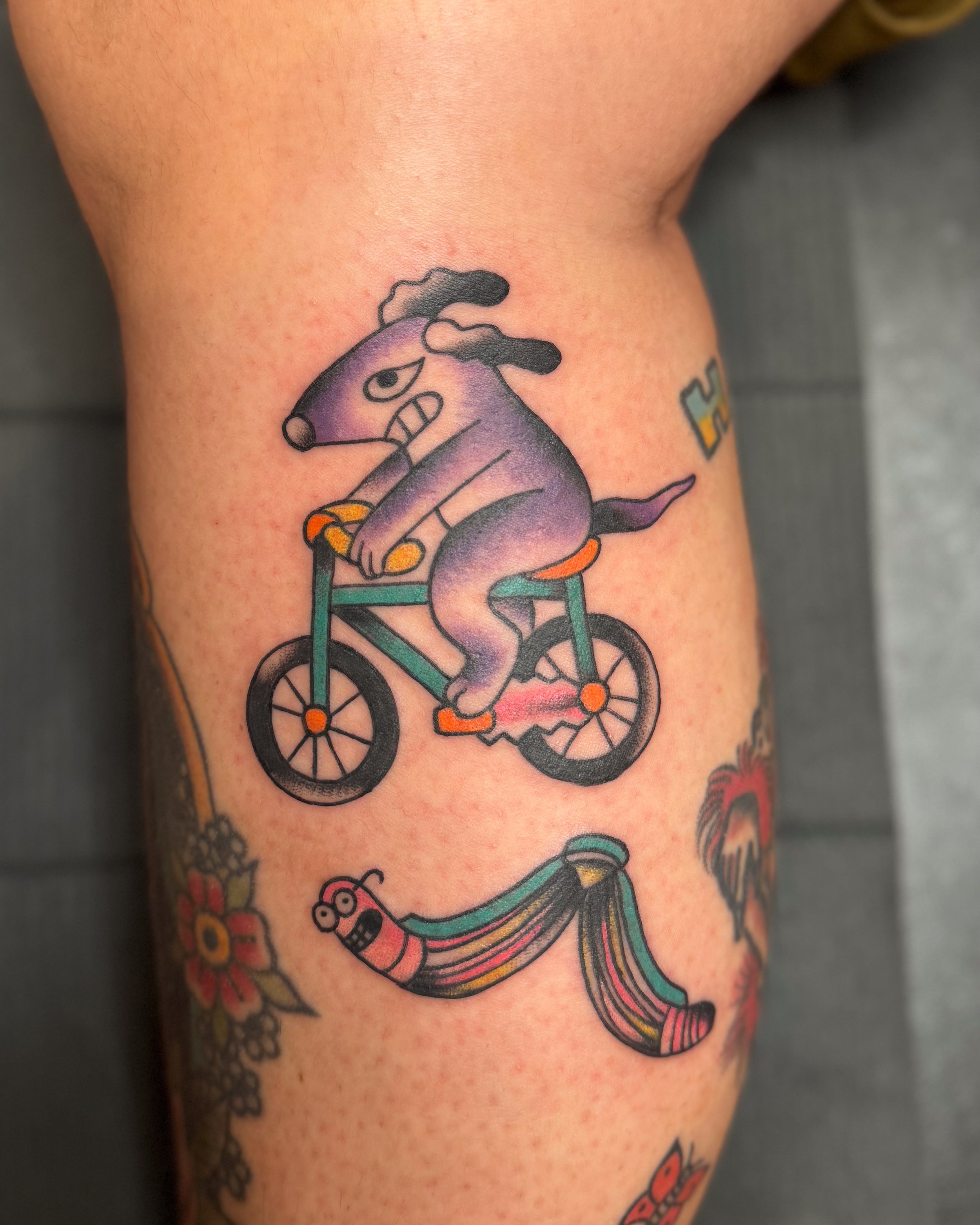 Tattoo of an angry dog riding a bicycle.