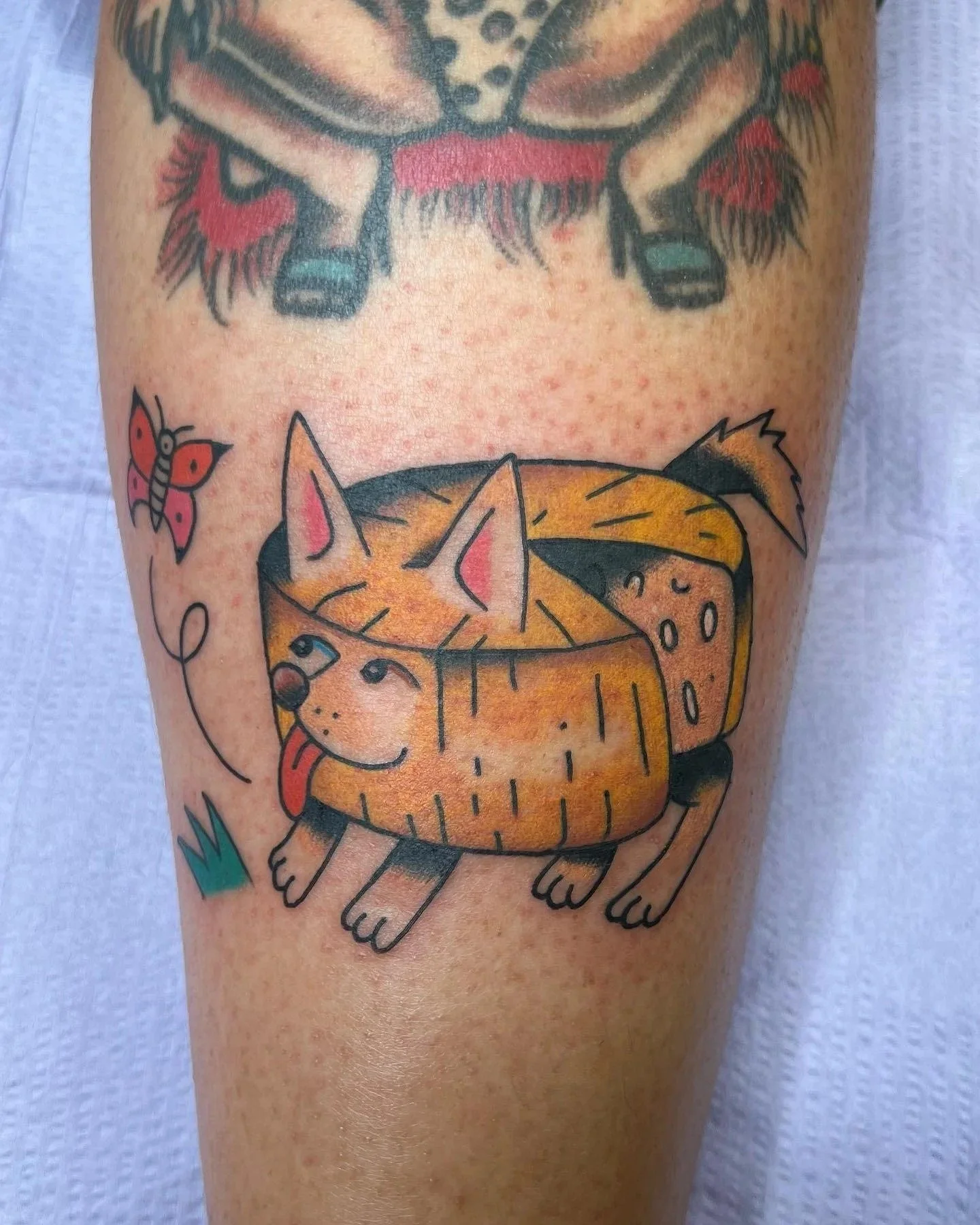 Tattoo of a cute Parmesan cheese dog, with tongue sticking out, and ears with pink inside.
