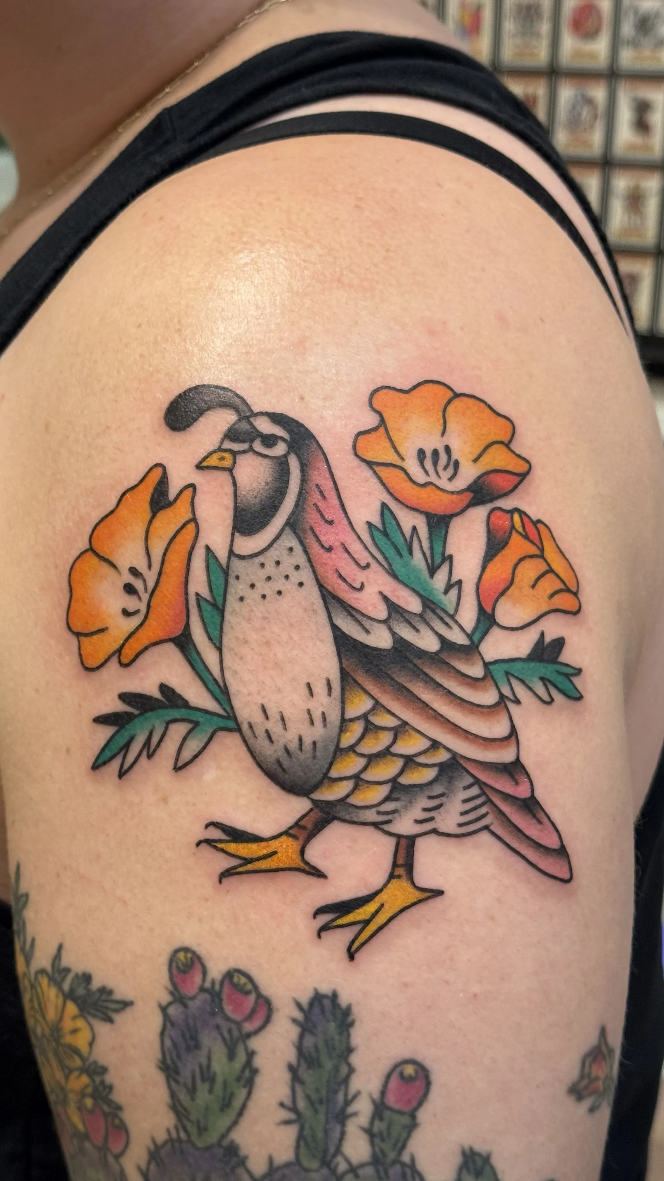 Tattoo of a bird with colorful flowers on shoulder skin.