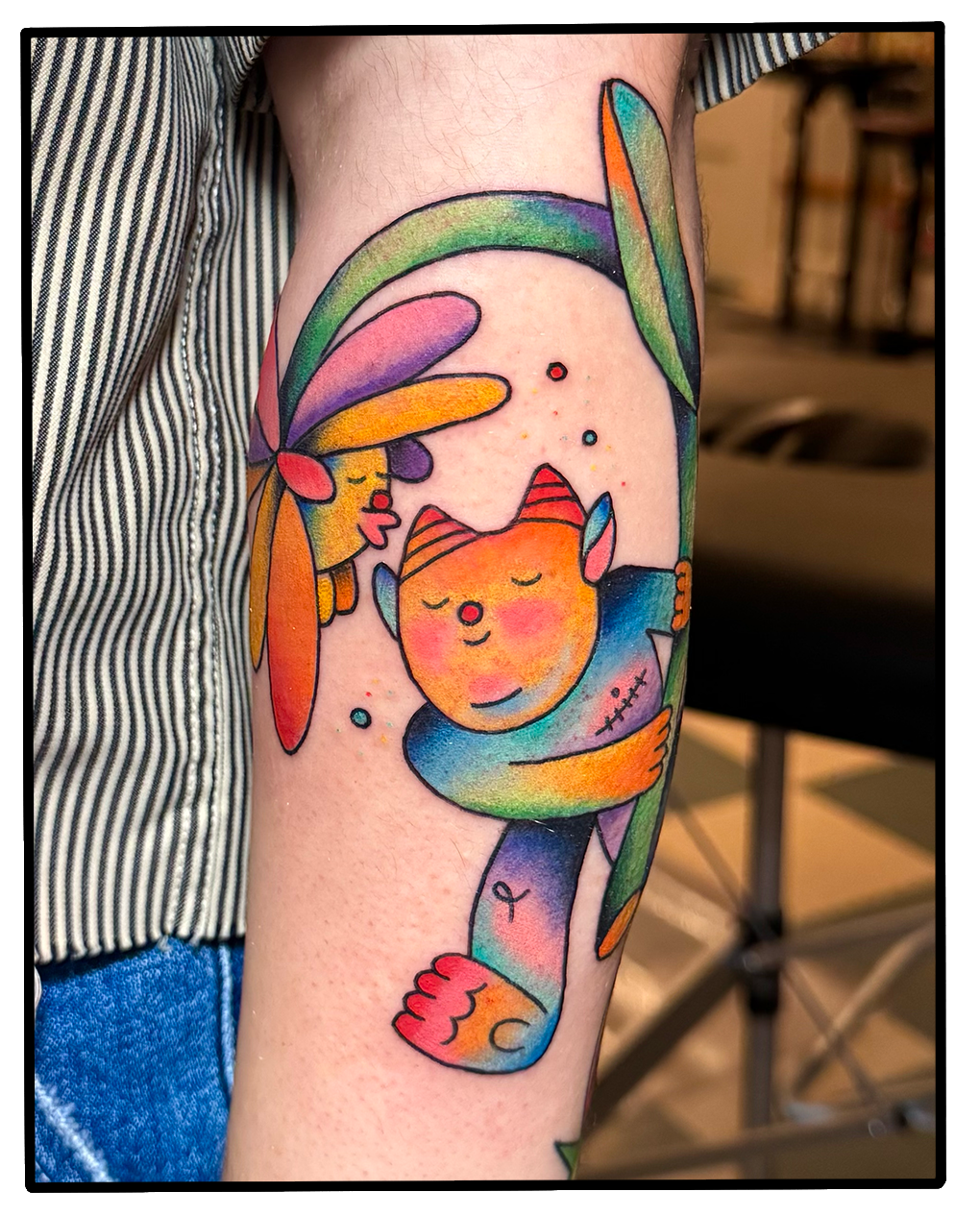 Colorful tattoo of a unicorn and a fairy hugging, with bright rainbow-like colors and a whimsical style.