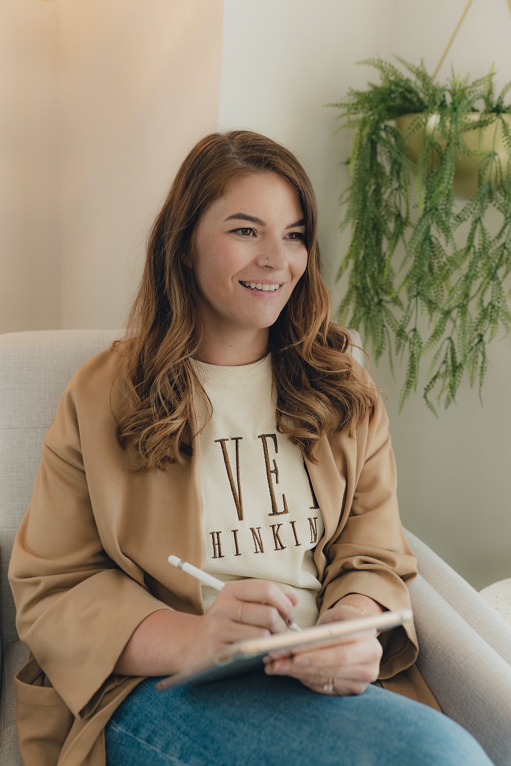 Registered psychologist in Alberta sitting in a therapy office, taking notes during a client session in a calm and supportive environment.