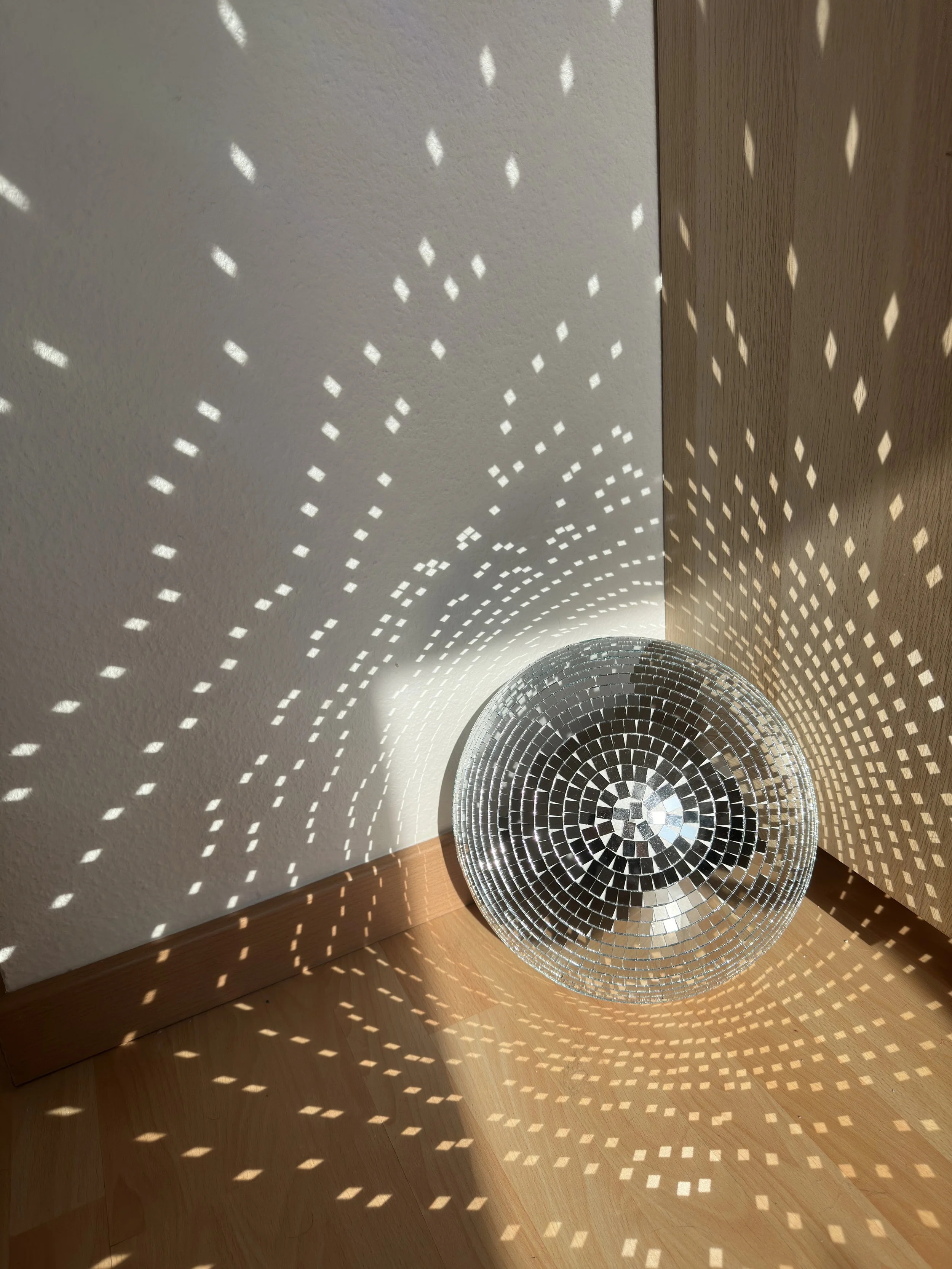 Disco ball casting reflections on wall and floor in corner of a room.