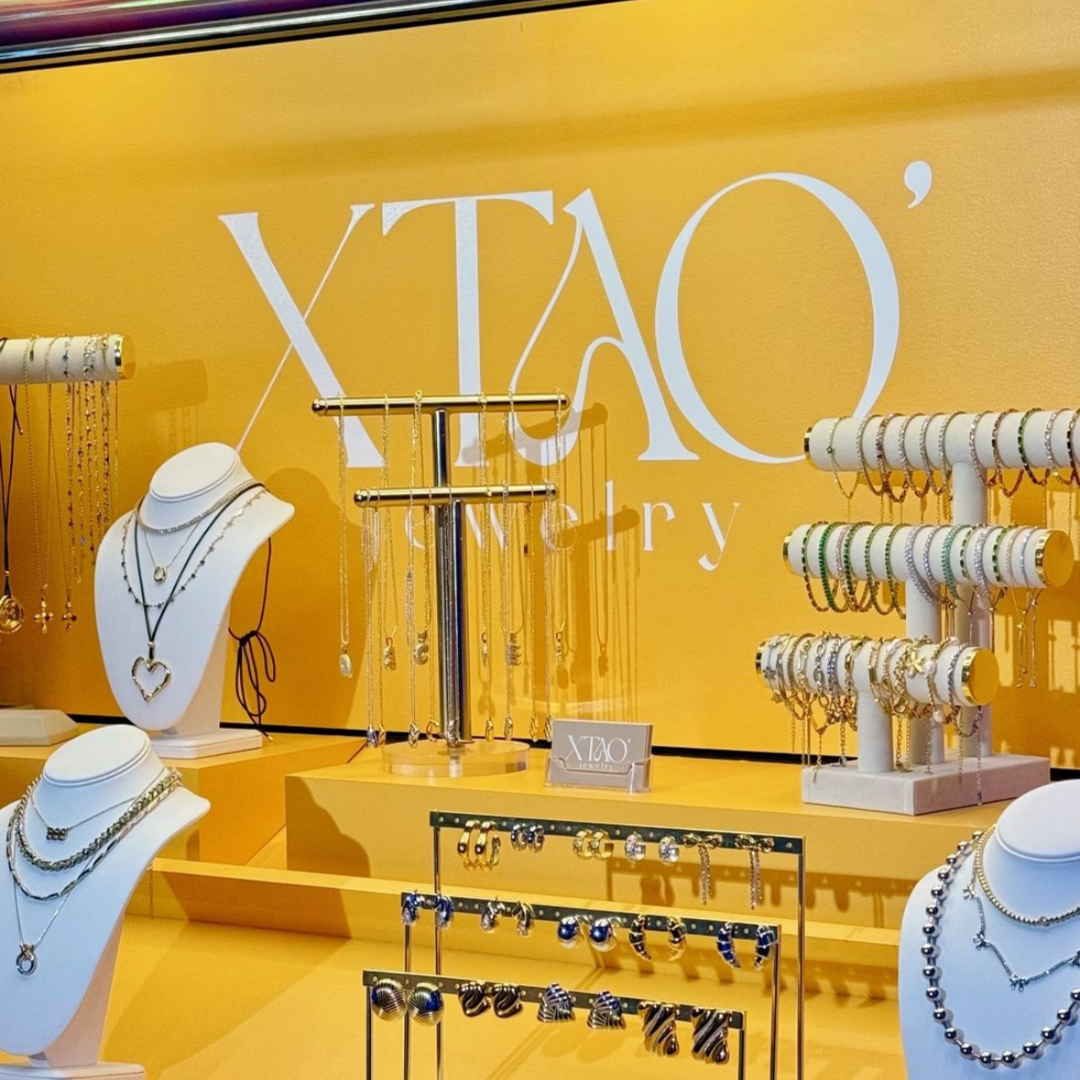 Jewelry display including necklaces, bracelets, and earrings with the brand "XTAO" on a yellow backdrop.