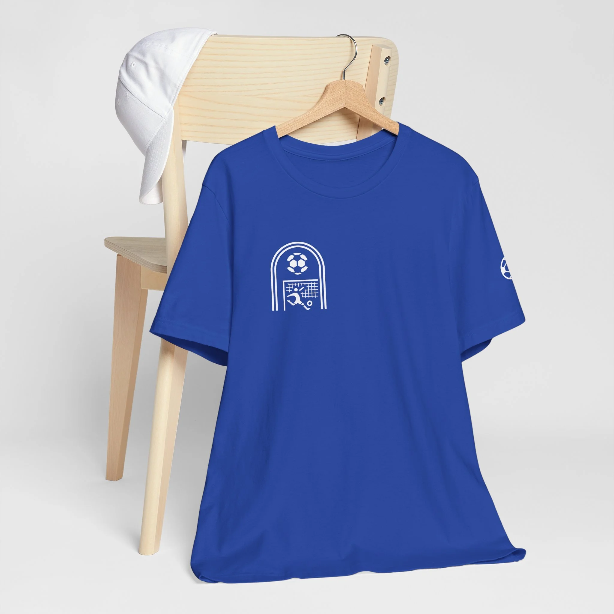Blue sports t-shirt hanging on a wooden hanger, with abstract tennis and soccer graphics on the front, placed against a minimalist background.