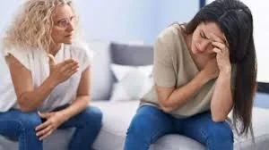 Two women having a serious conversation; one appears upset, the other is speaking and gesturing.